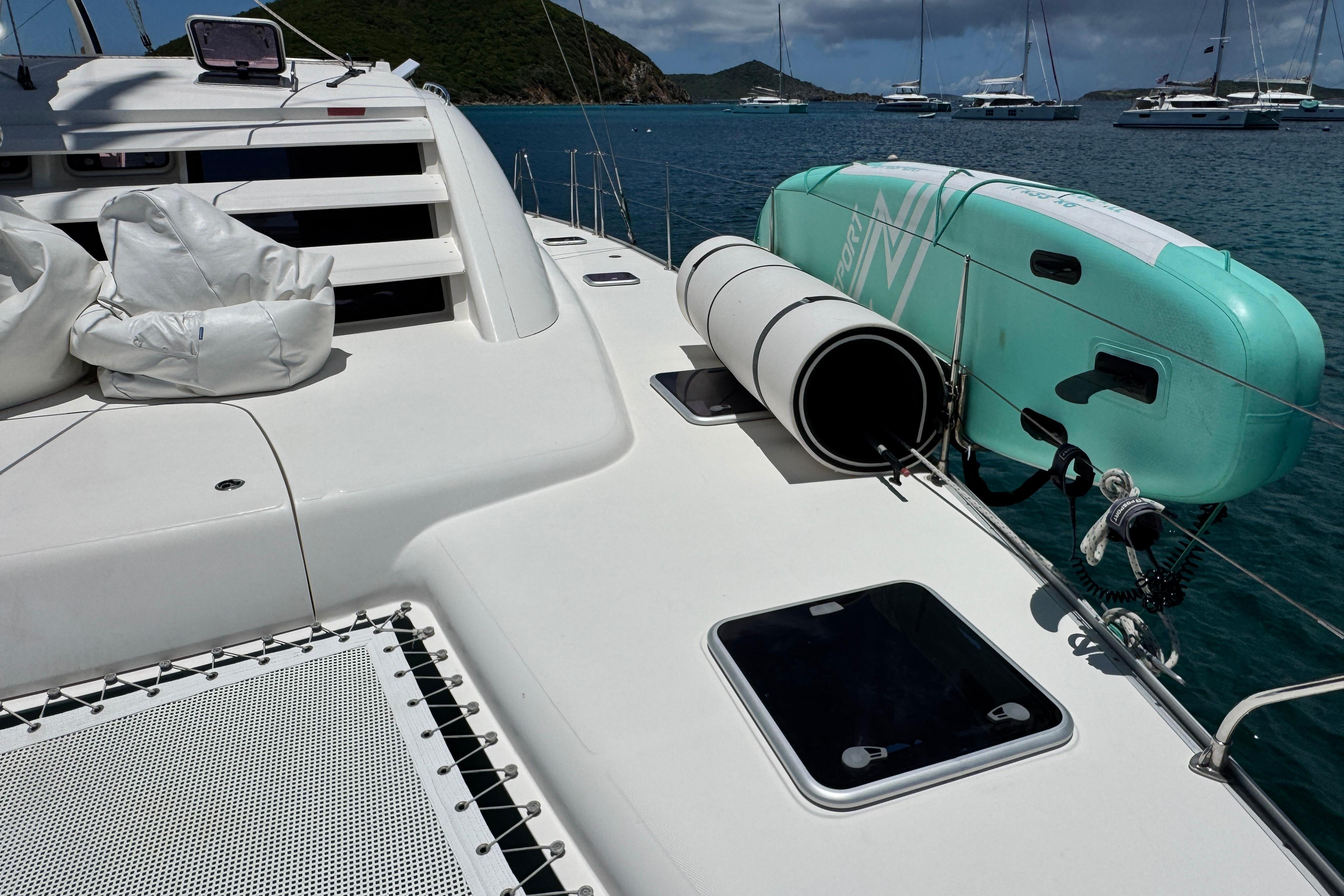Leopard 46 yacht deck with paddleboard, ocean view, and moored boats in the background.