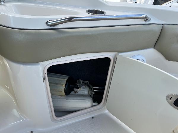 Open storage compartment on 2005 Sea Ray 220 Sundeck boat, showing interior equipment.