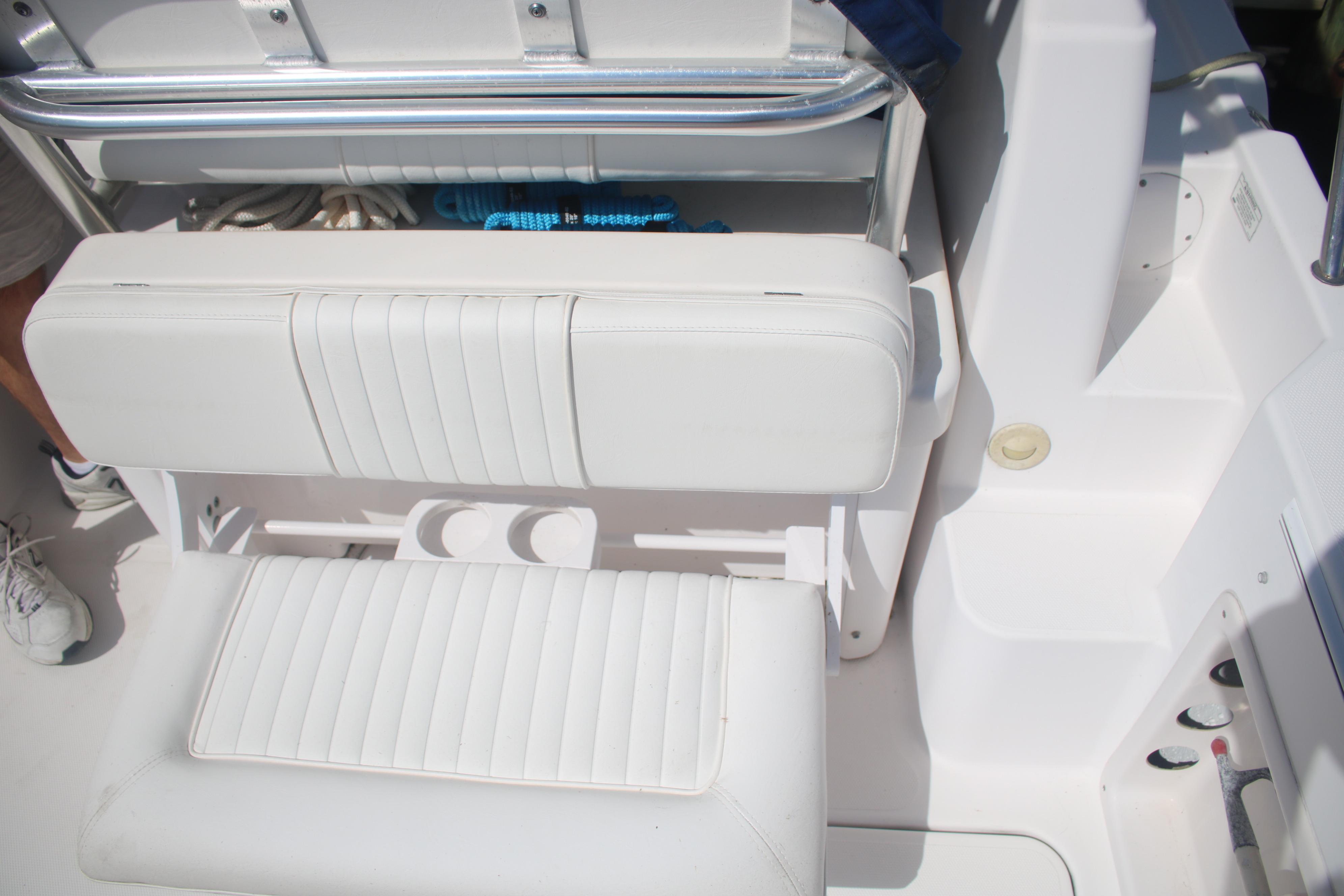 White seating area on a 2011 Larson Carbiro 240 boat, featuring storage and cup holders.
