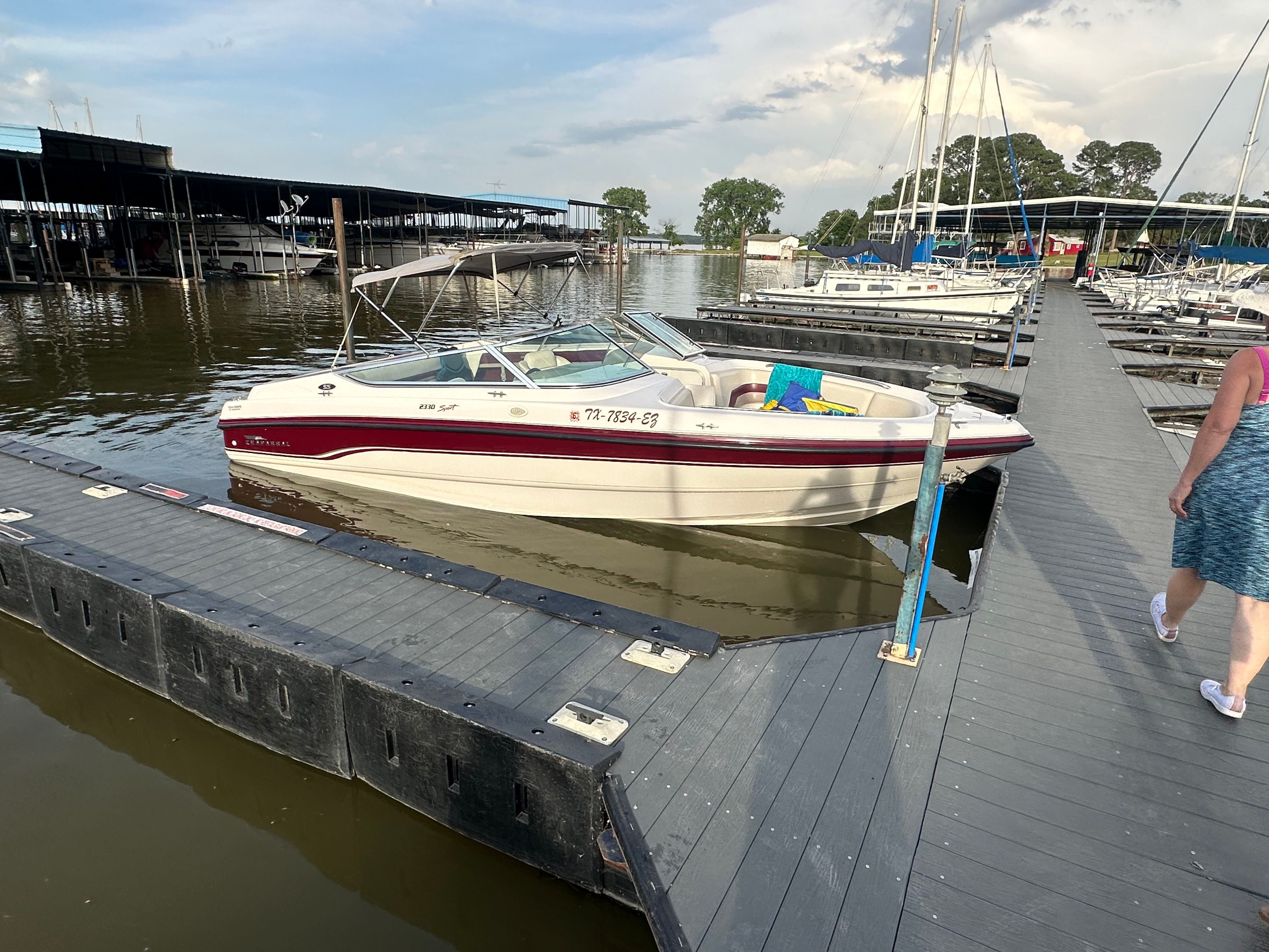 A 1995 Chaparral 2330 boat docked at a marina, with calm water and other boats nearby.