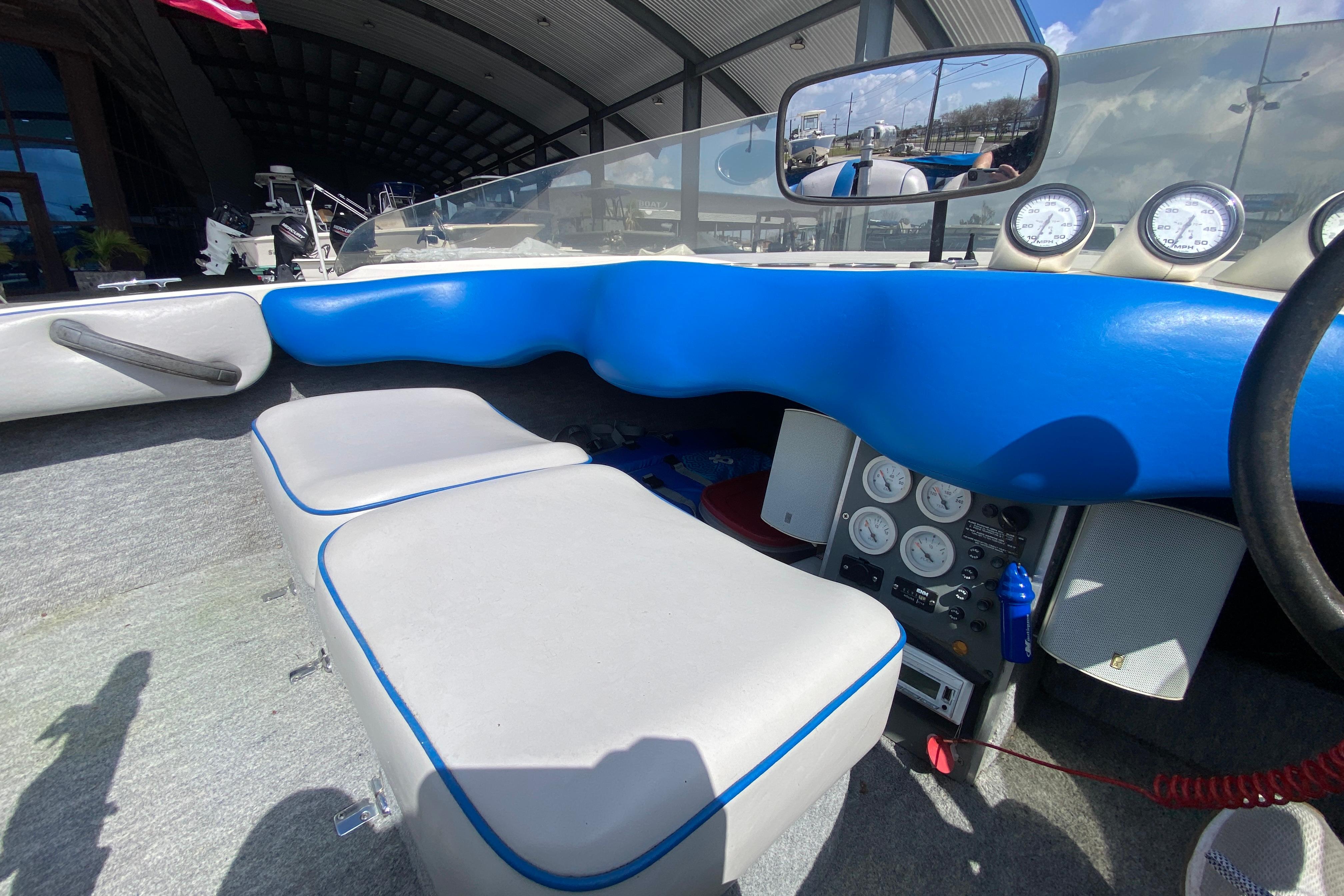 Interior of a 1997 Malibu Tantrum boat with blue and gray seating, dashboard gauges.