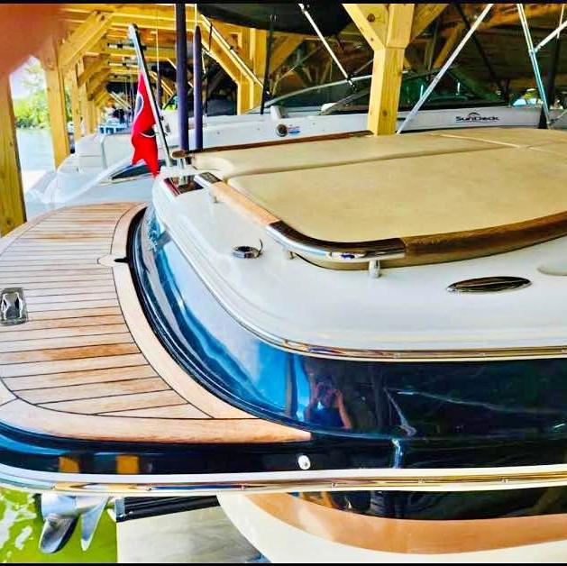 2016 Chris-Craft Carina 21 boat with wooden deck, docked under a wooden shelter.