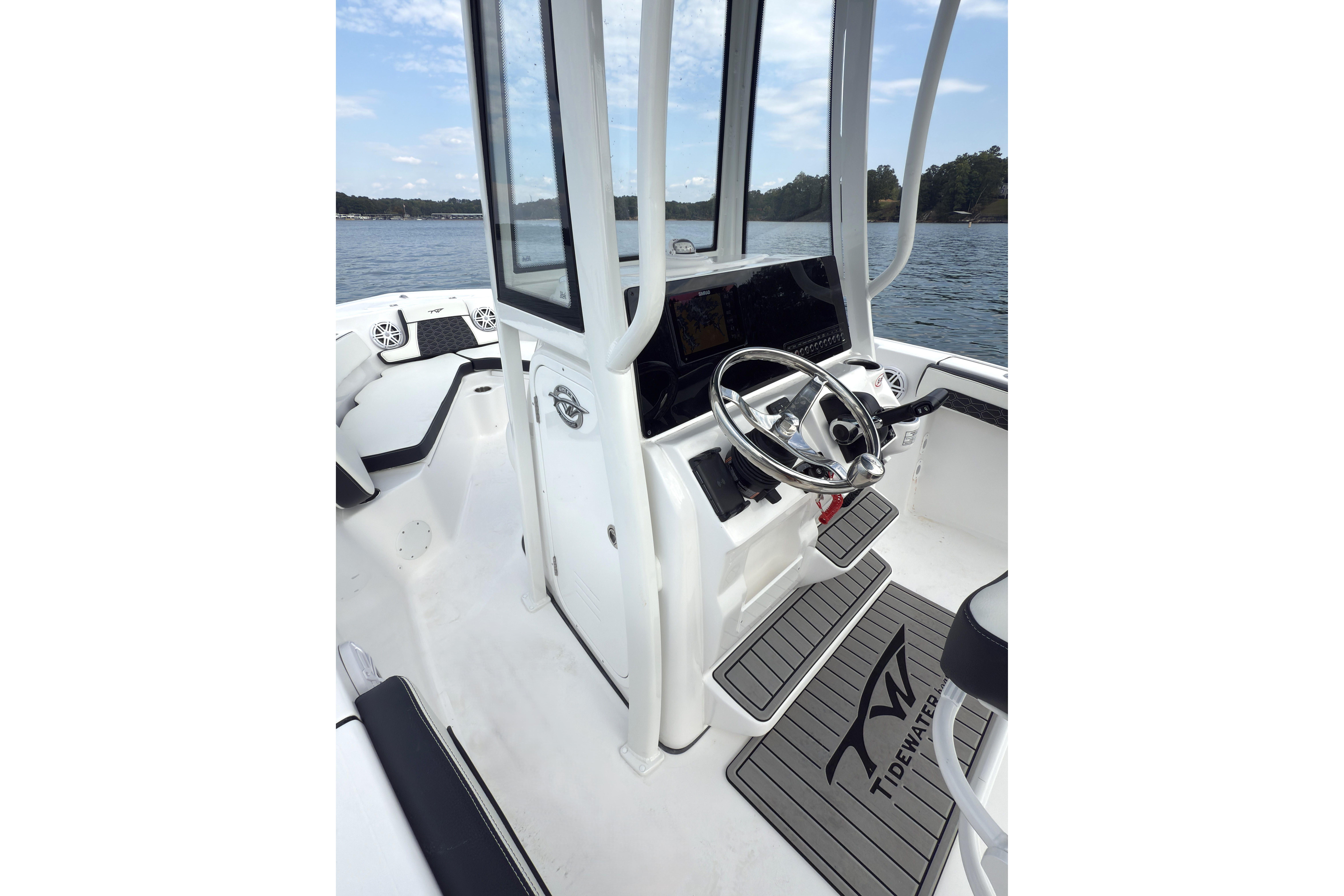 2026 Tidewater 210 CC Adventure boat interior with steering wheel and console on a lake.