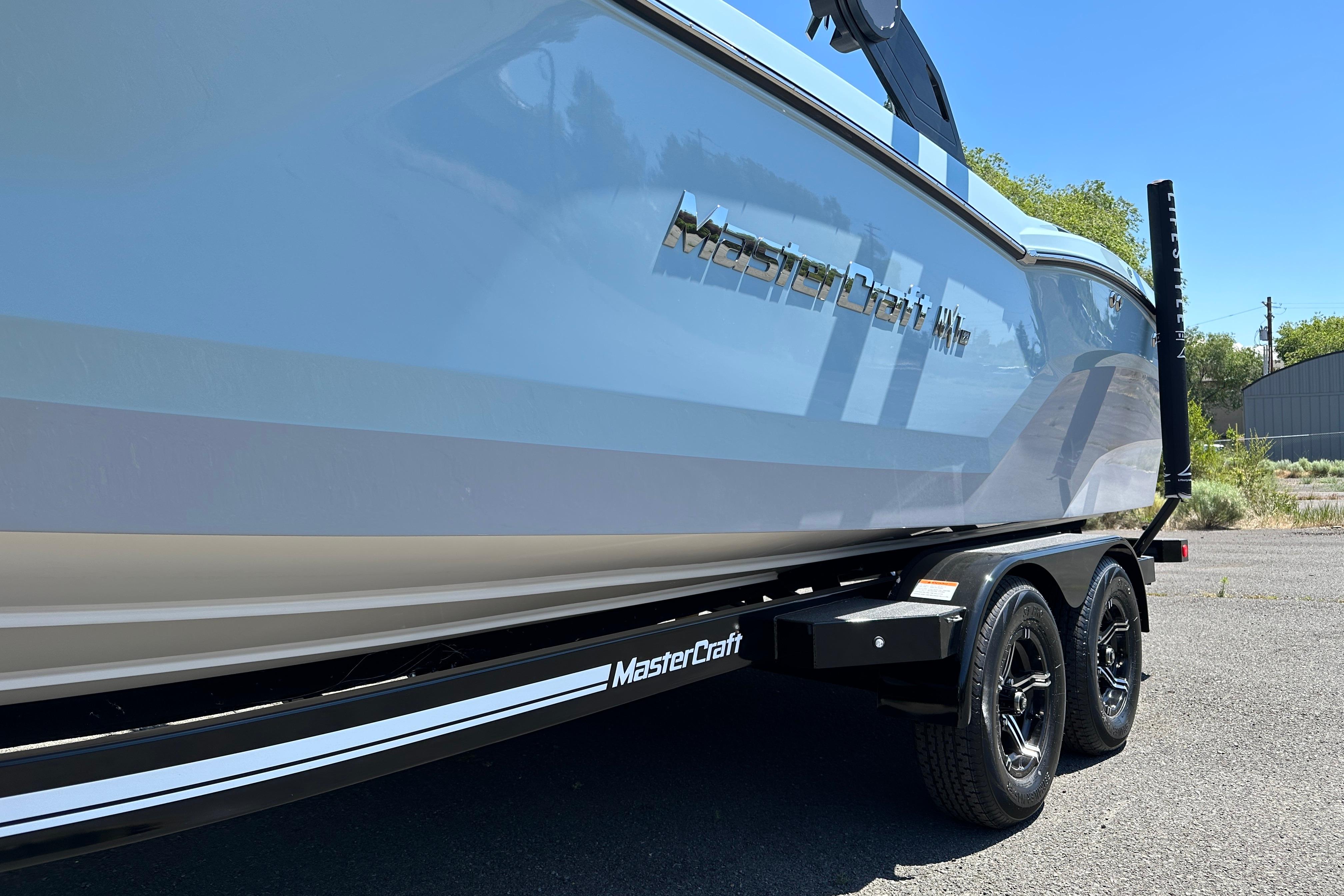 2023 MasterCraft NXT23 boat on trailer, side view, sunny day.
