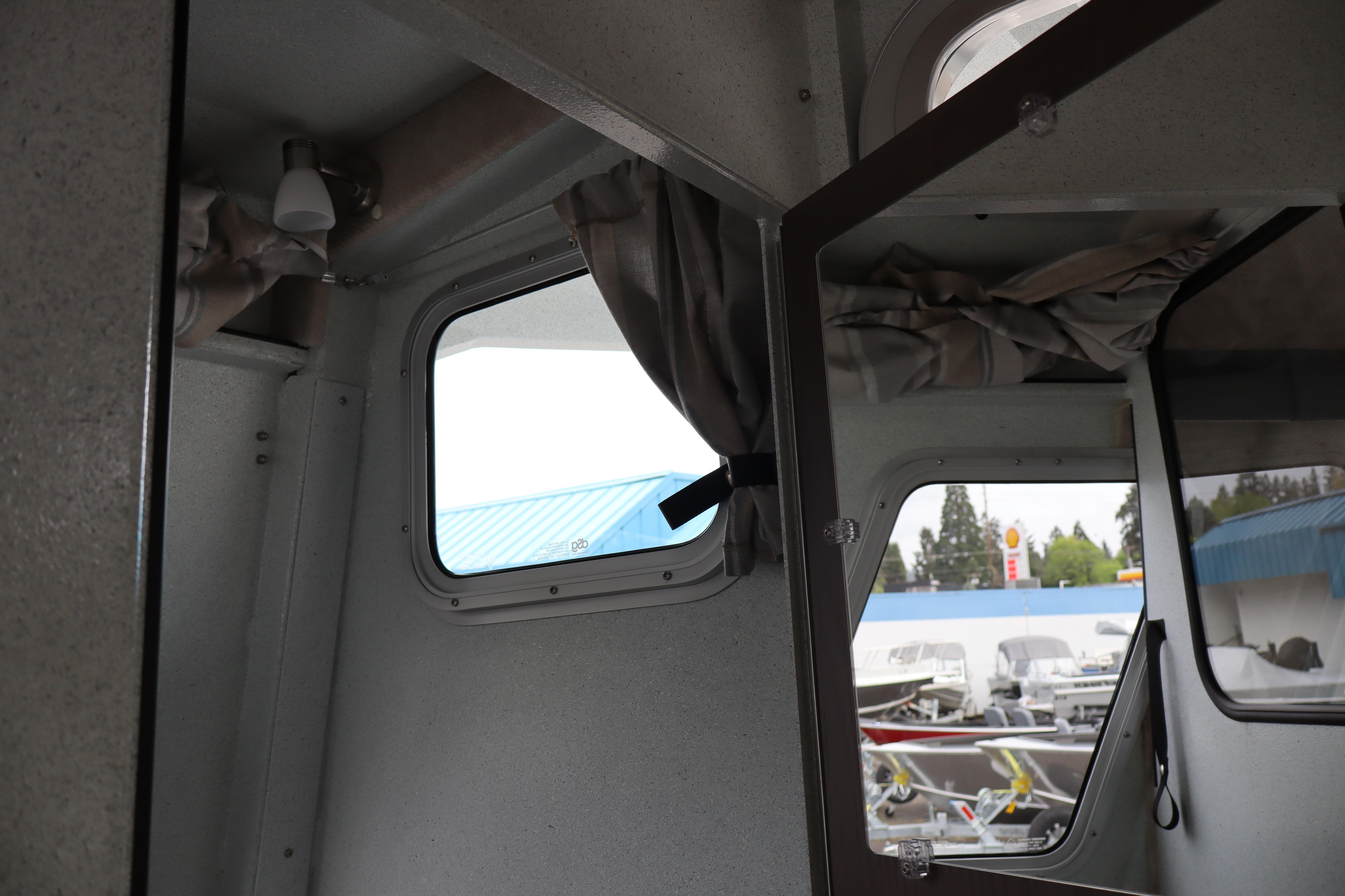 Interior view of 2026 KingFisher 3025 XRS boat, showcasing windows and curtains.