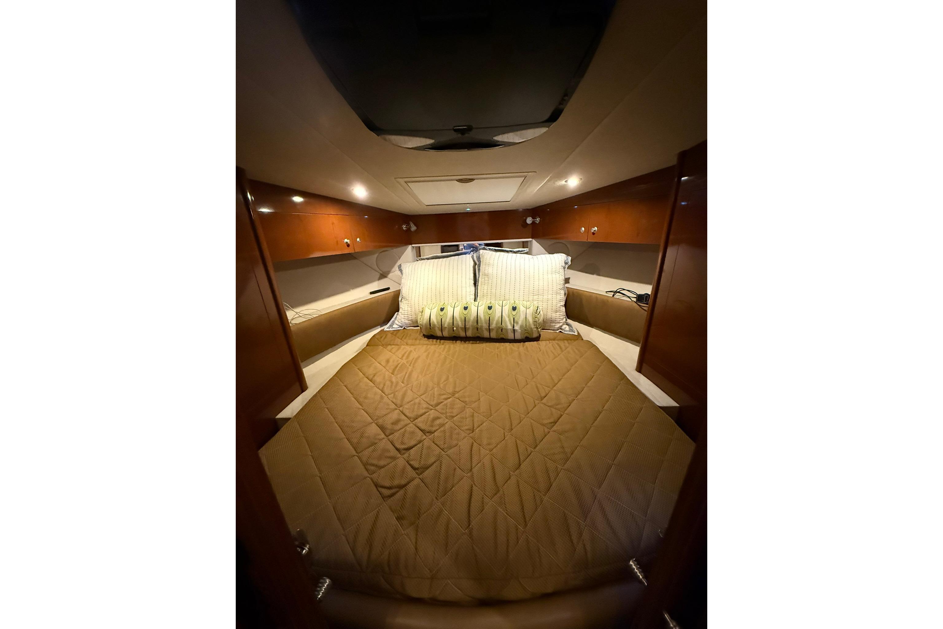 Interior cabin of 2009 Sea Ray 350 Sundancer with cozy bed and wooden accents.
