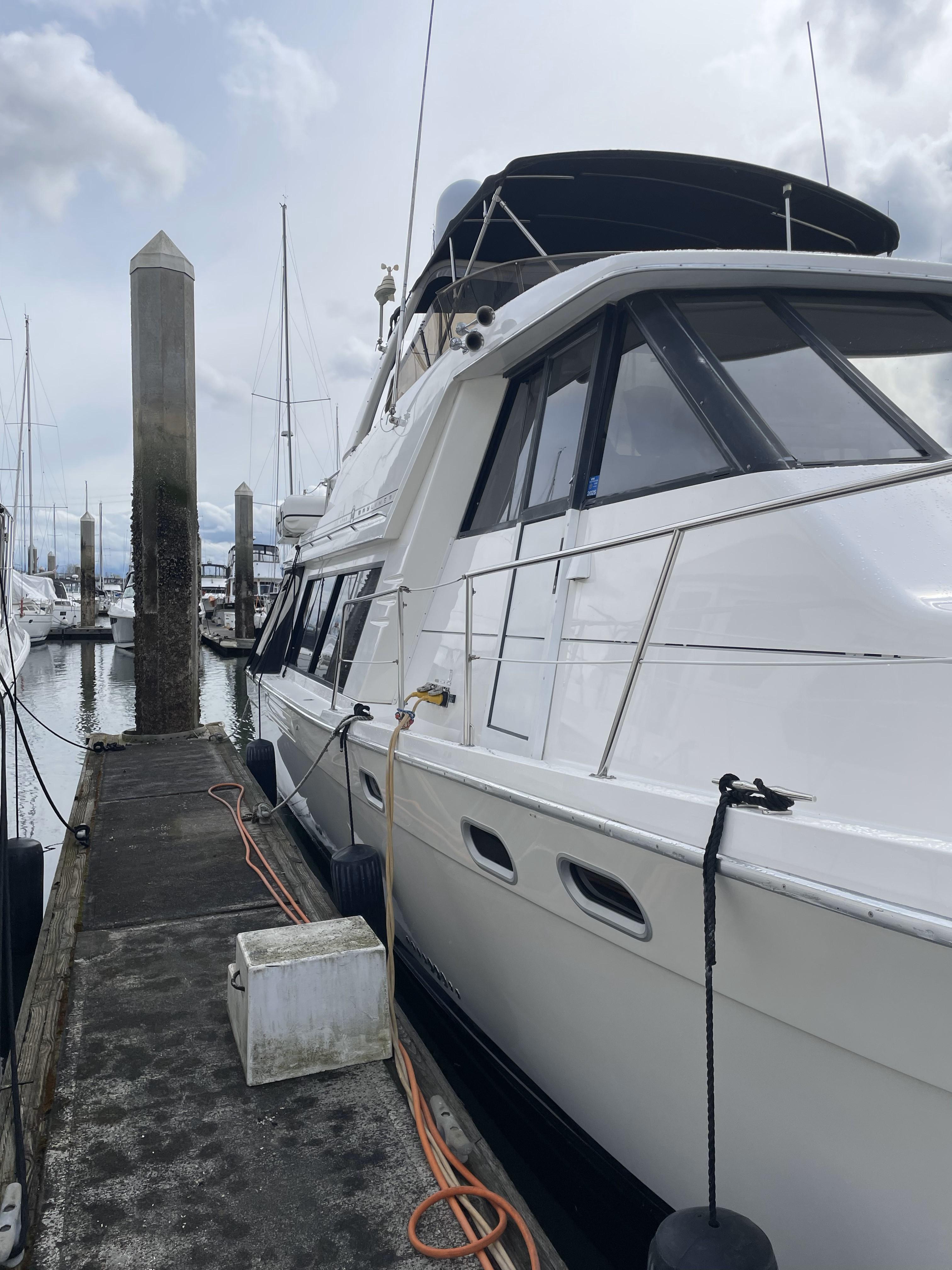 1995 Bayliner 4788 Pilot House Motoryacht docked at marina, overcast sky.