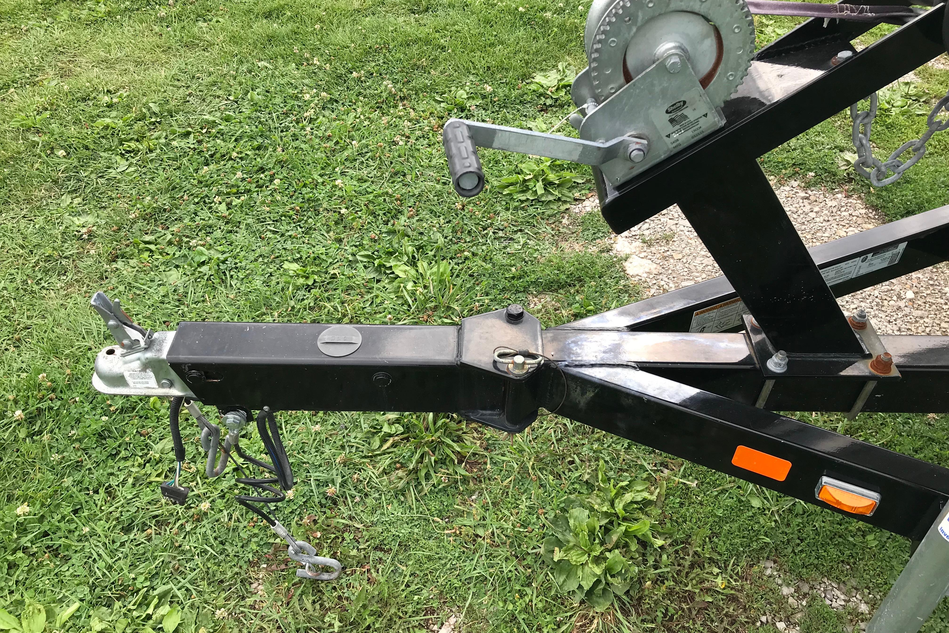 Trailer hitch and winch of a 2015 Crownline 18 SS boat on grassy ground.