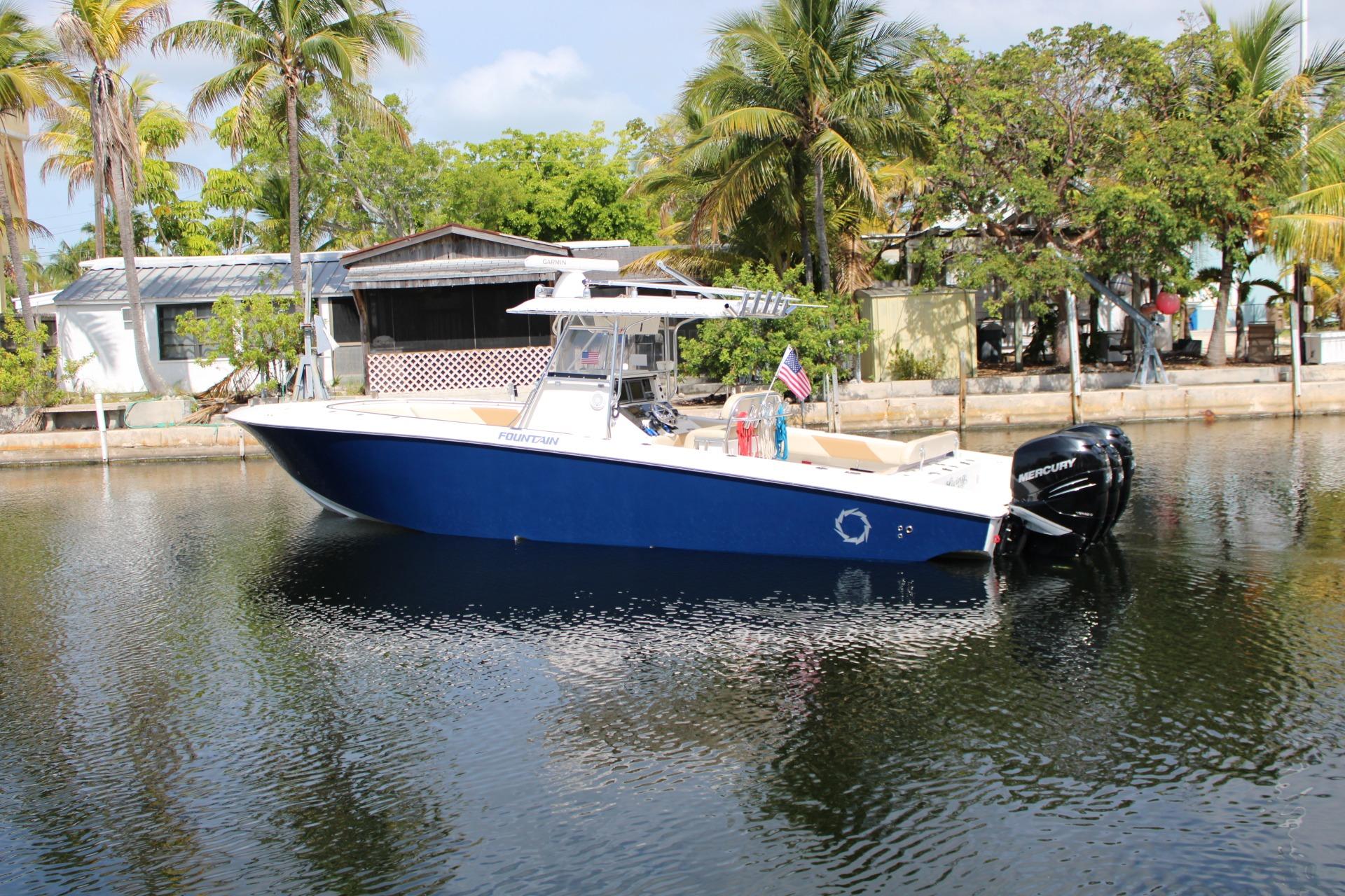 2007 Fountain 34 Center Console boat on calm water, surrounded by tropical trees.