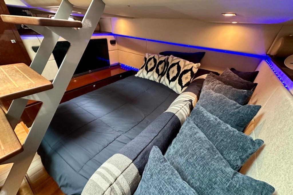 Luxurious cabin interior of 2011 Sea Ray 450 Sundancer with cozy bedding and ambient lighting.