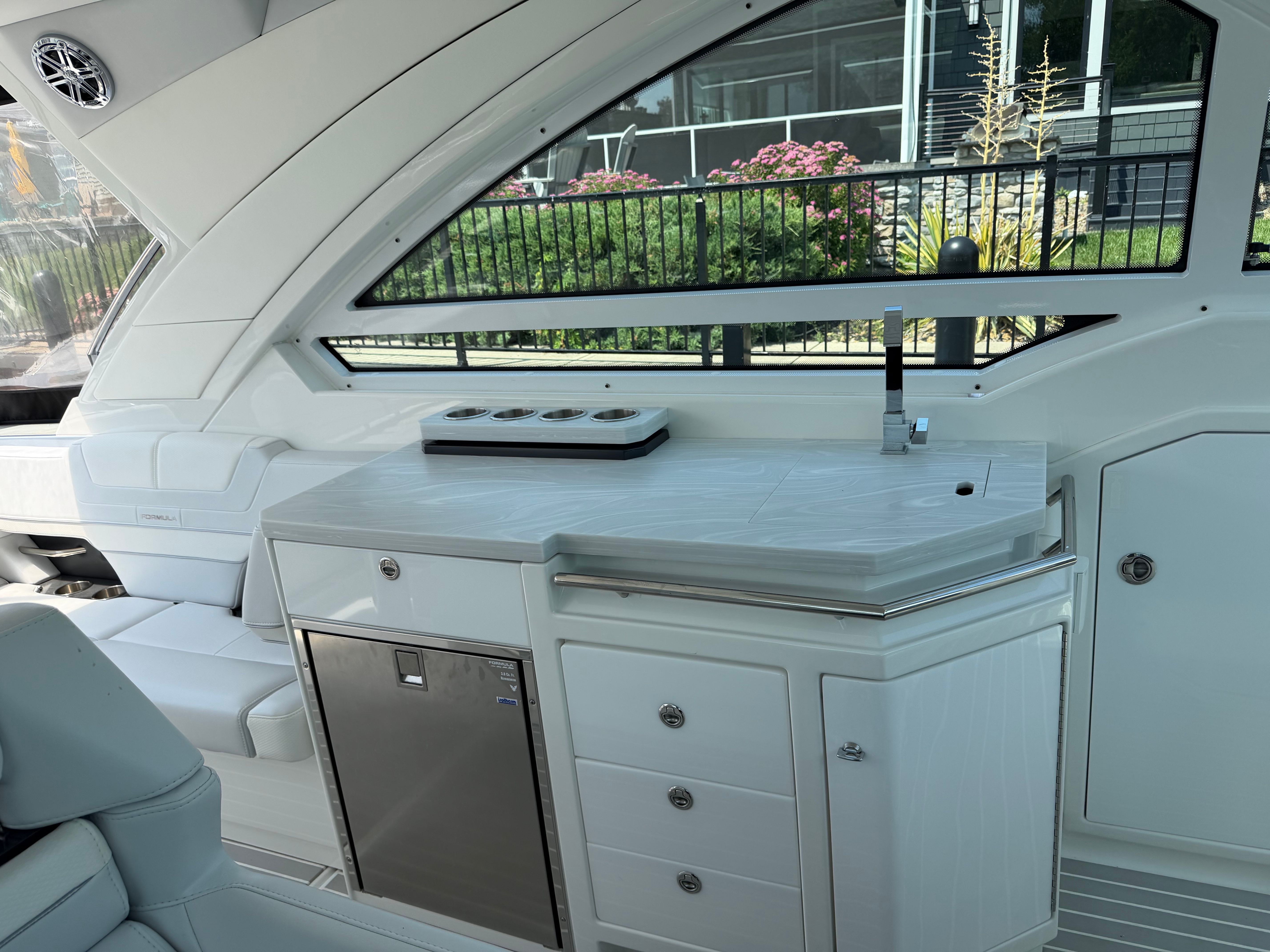The interior of a modern yacht features a sleek kitchenette with a sink and refrigerator.