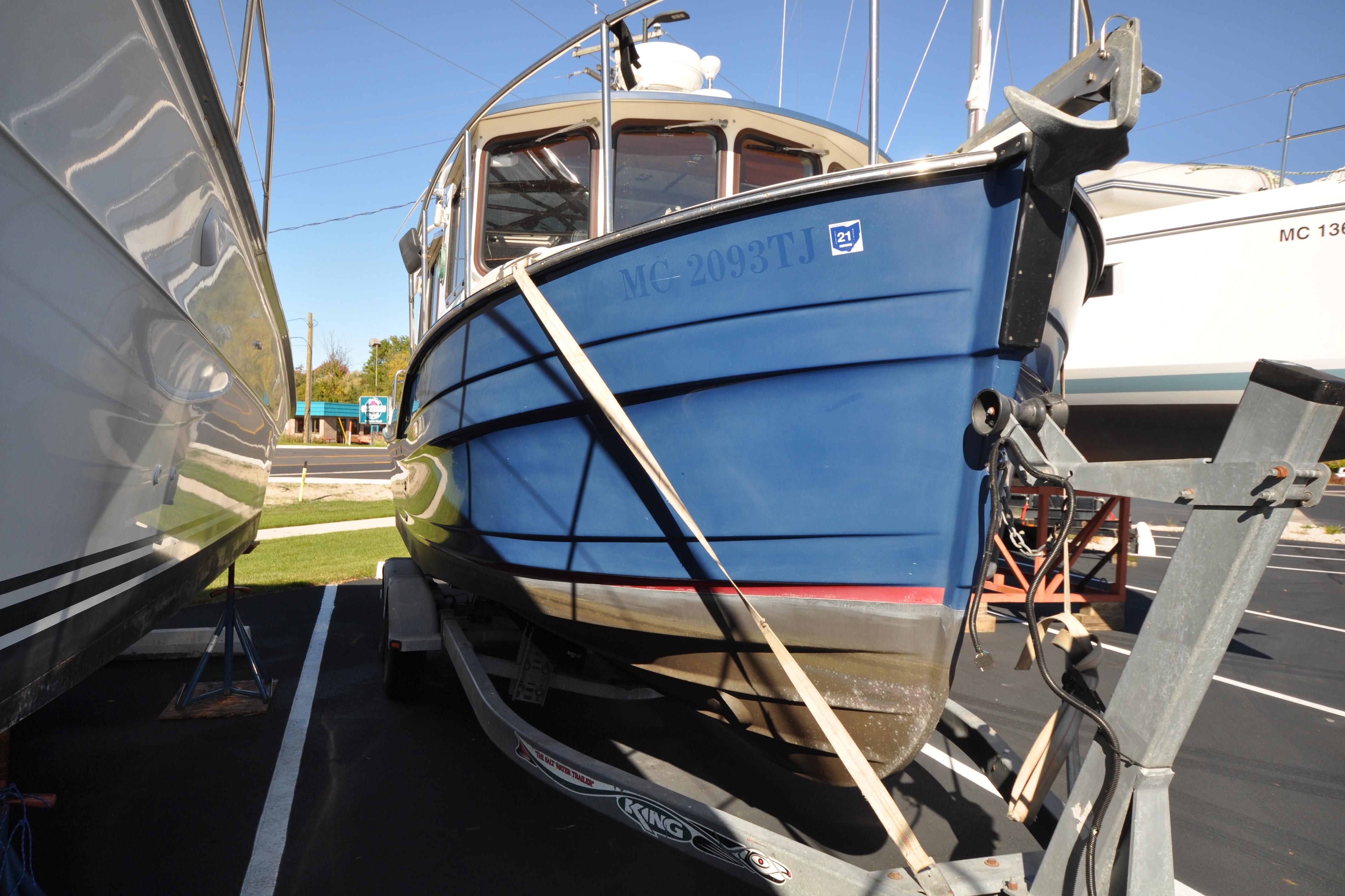 2007 Ranger Tug R-25 boat on trailer, blue hull, parked outdoors.