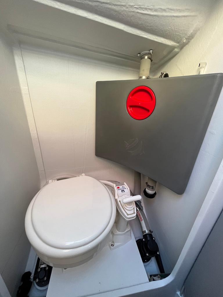 Compact marine toilet in a Seascape 27 sailboat, 2018 model, with manual flush system.