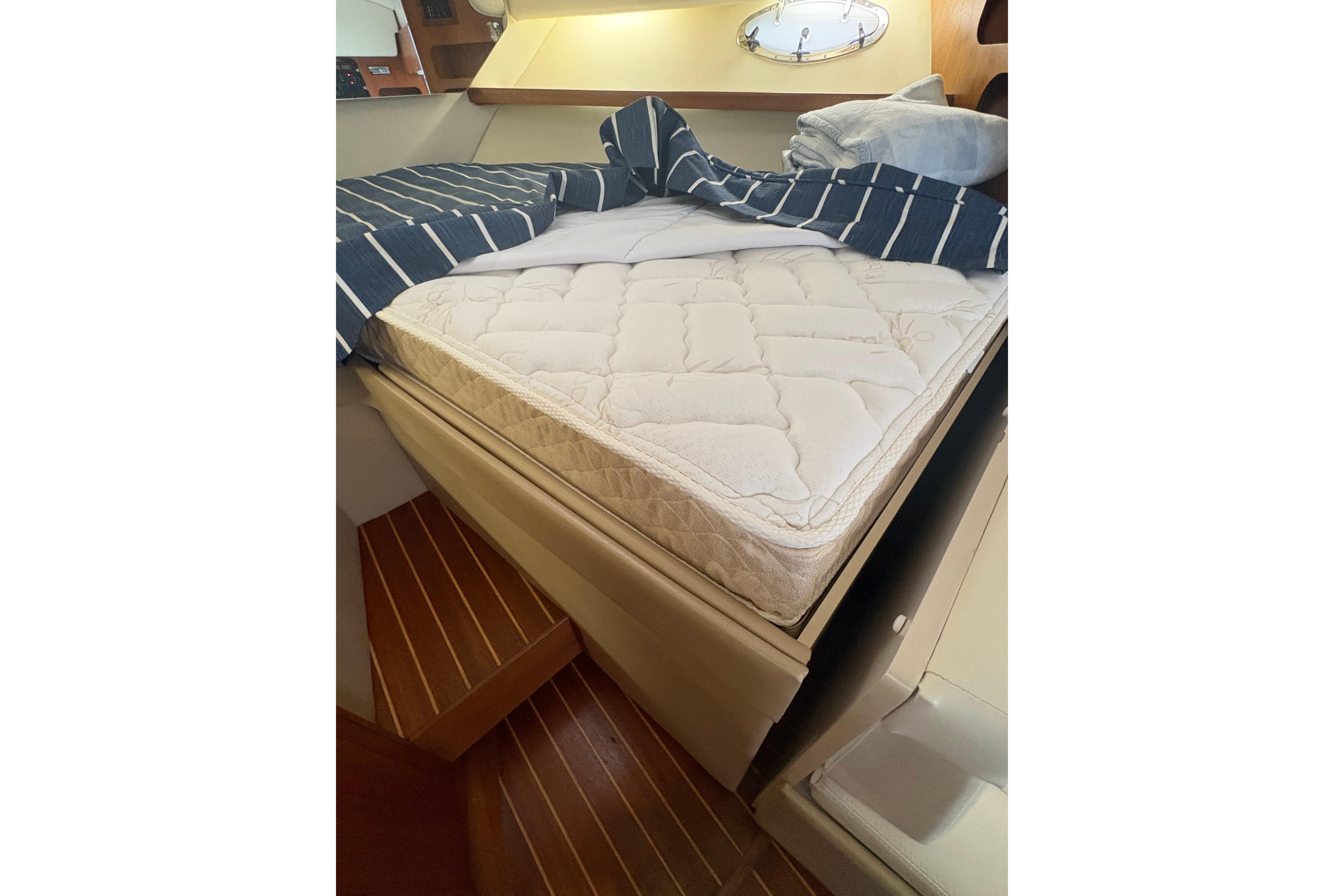 Interior cabin of 1999 Tiara Yachts 3100 Open with bed and striped bedding.