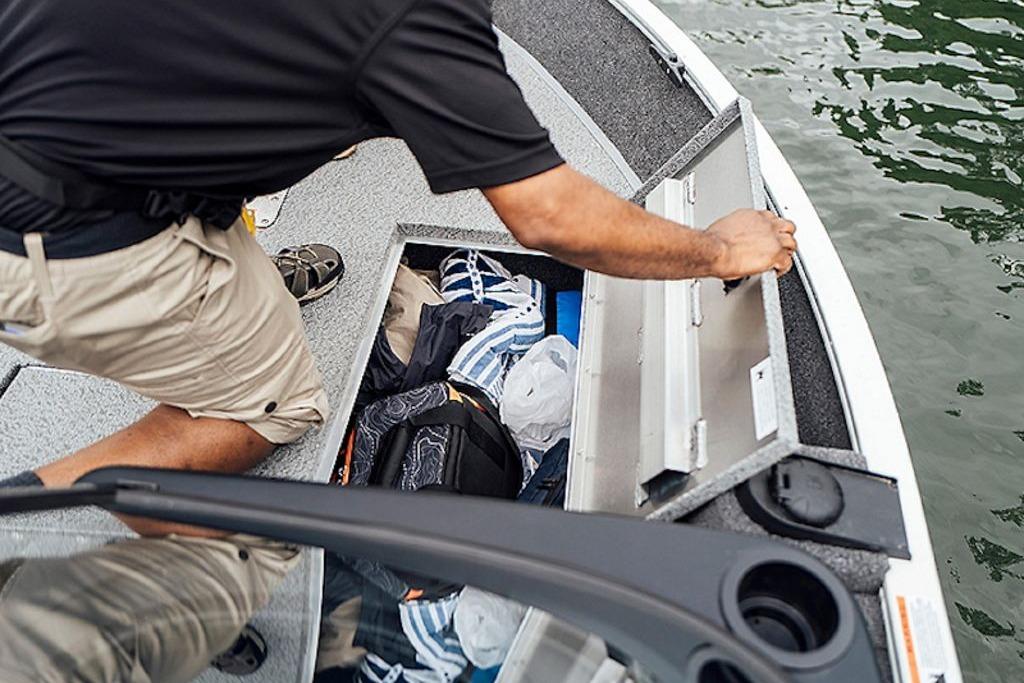 Man accessing storage on 2026 Lowe Fishing Machine 175 boat.