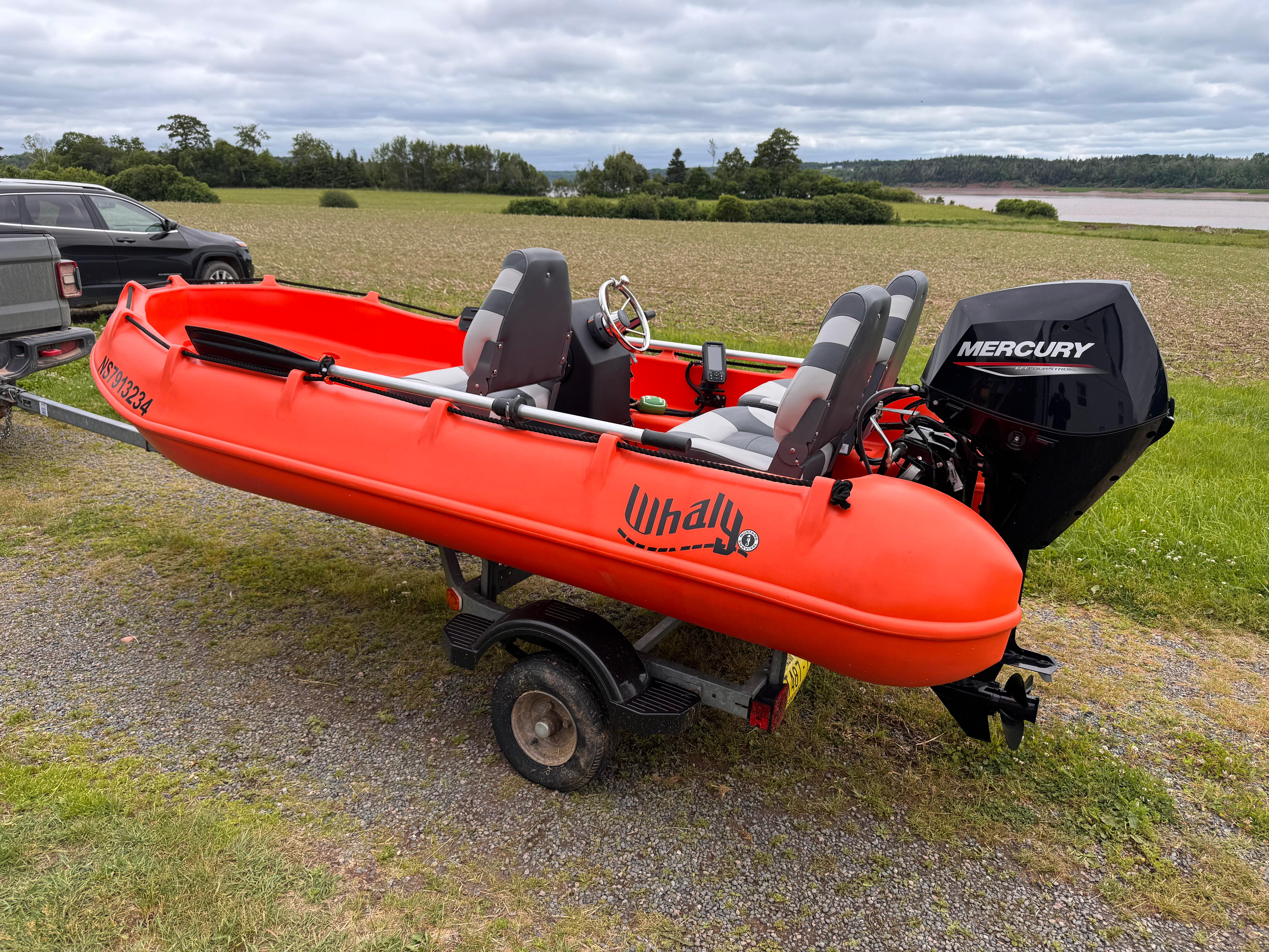 Red 2021 Whaly 370 boat with Mercury engine on a trailer, parked in a rural area.