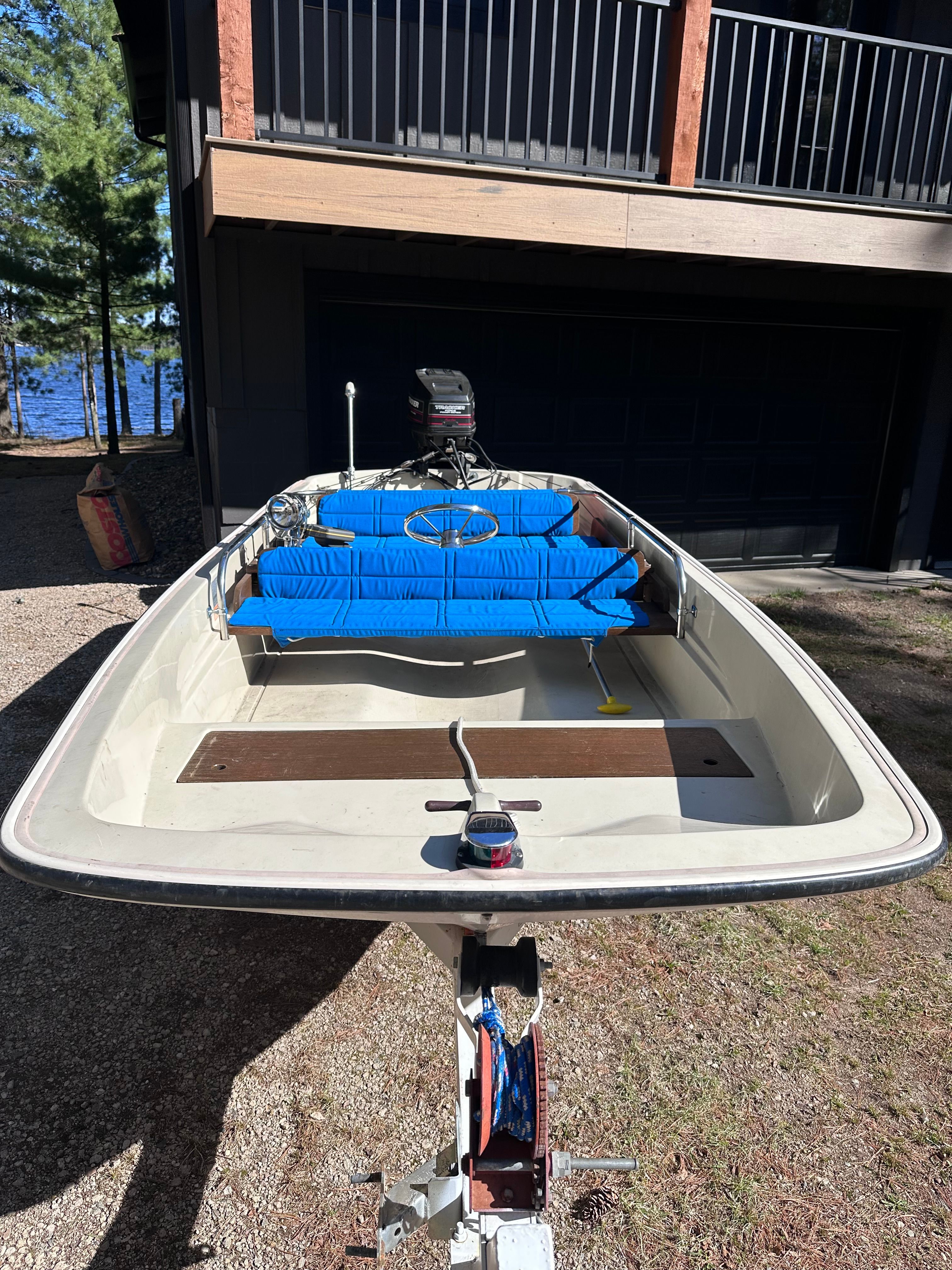 1973 Boston Whaler Sourpuss boat with blue seats in front of a house.