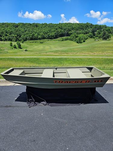 2025 Tracker Grizzly 1036 Utility boat on pavement, green landscape background.