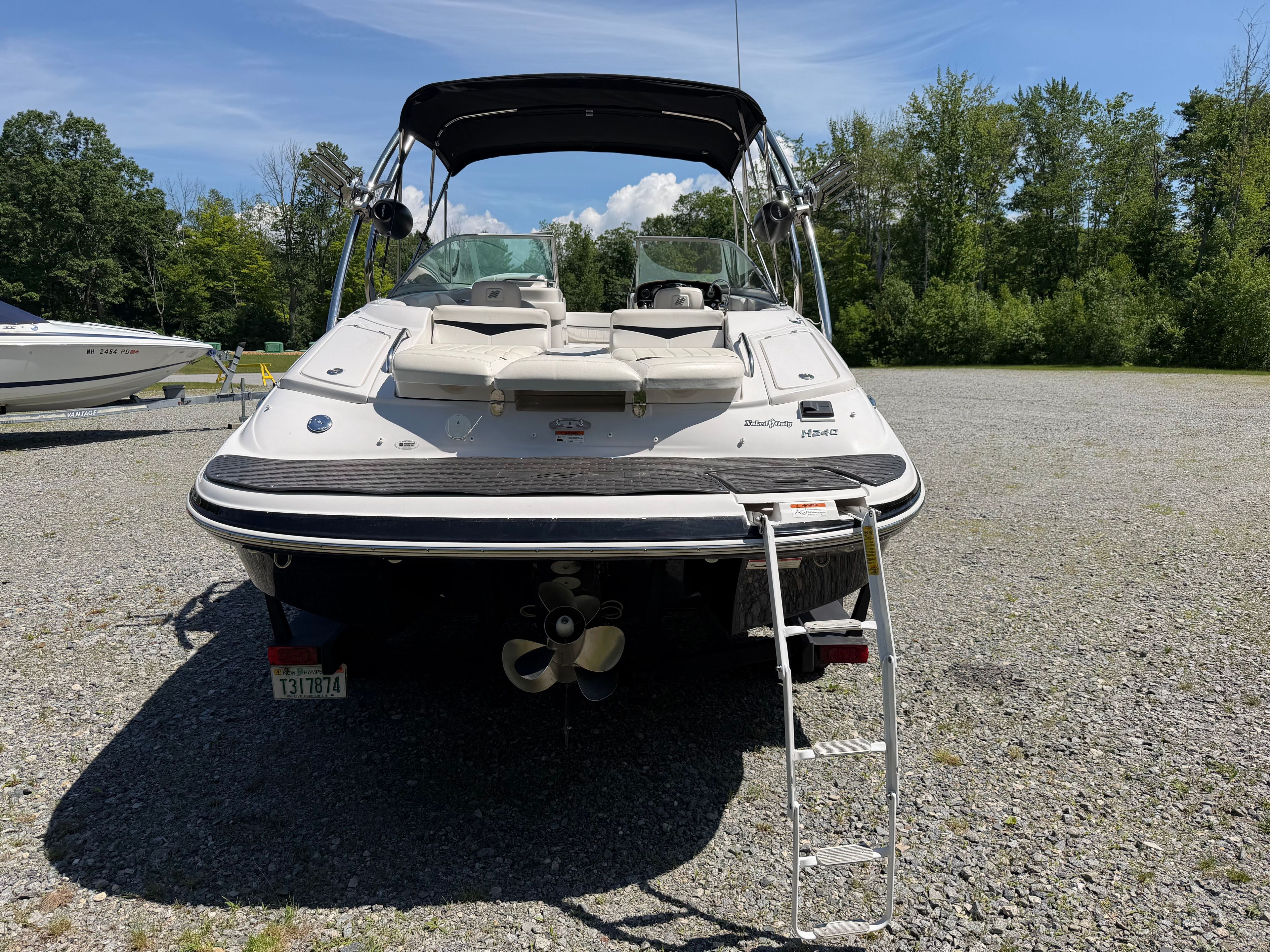 2008 Four Winns H240 Frenzy with sunbathing area and swim ladder, parked on gravel.