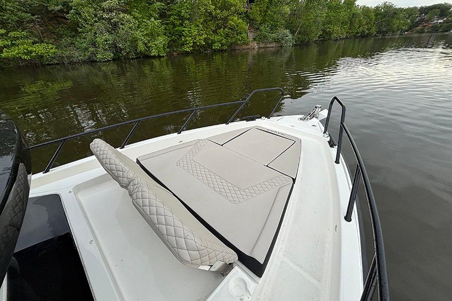 Front deck of 2026 Navan C30 boat with cushioned seating, near lush riverbank.