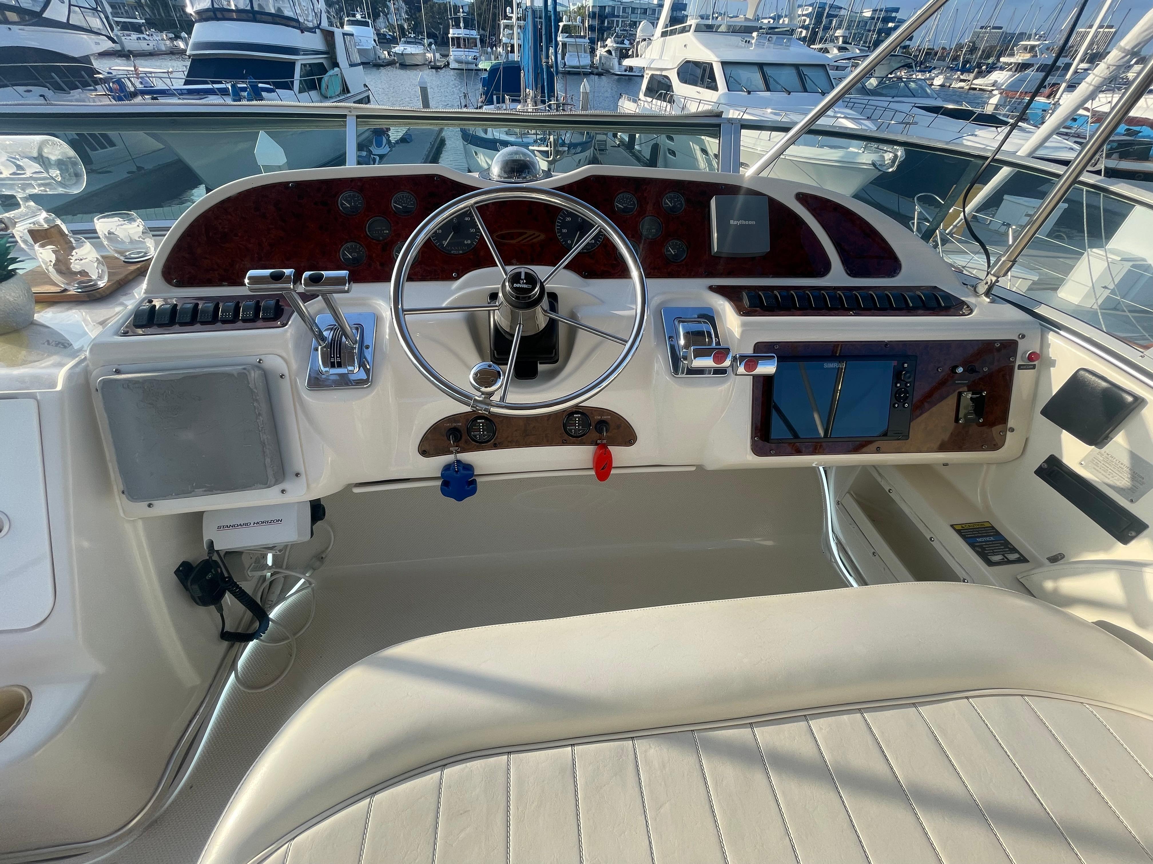 1998 Maxum 4100 SCA yacht helm with steering wheel and navigation controls at marina.