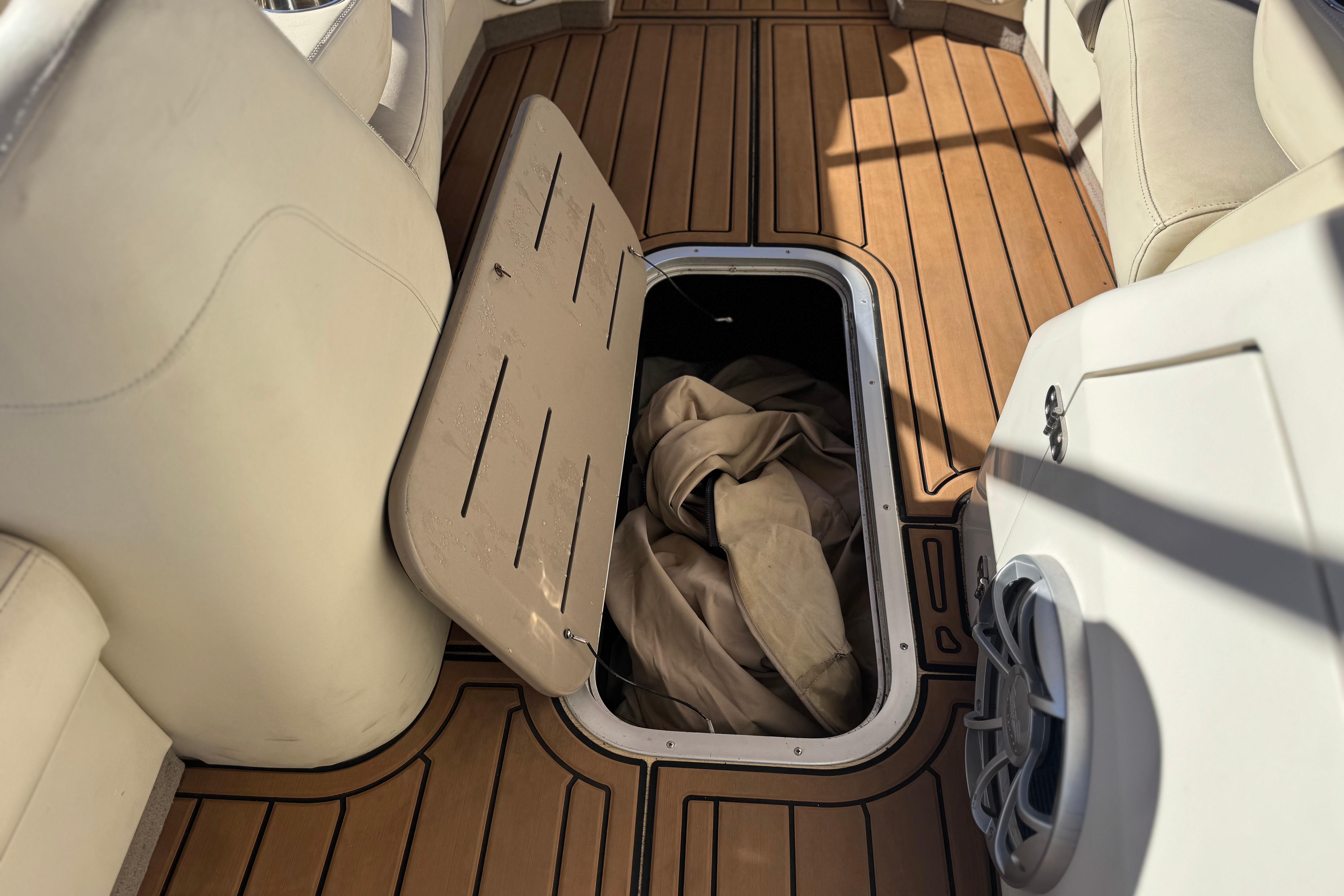 2013 Bennington 2575QCW I/O boat interior with open storage compartment on wooden deck.