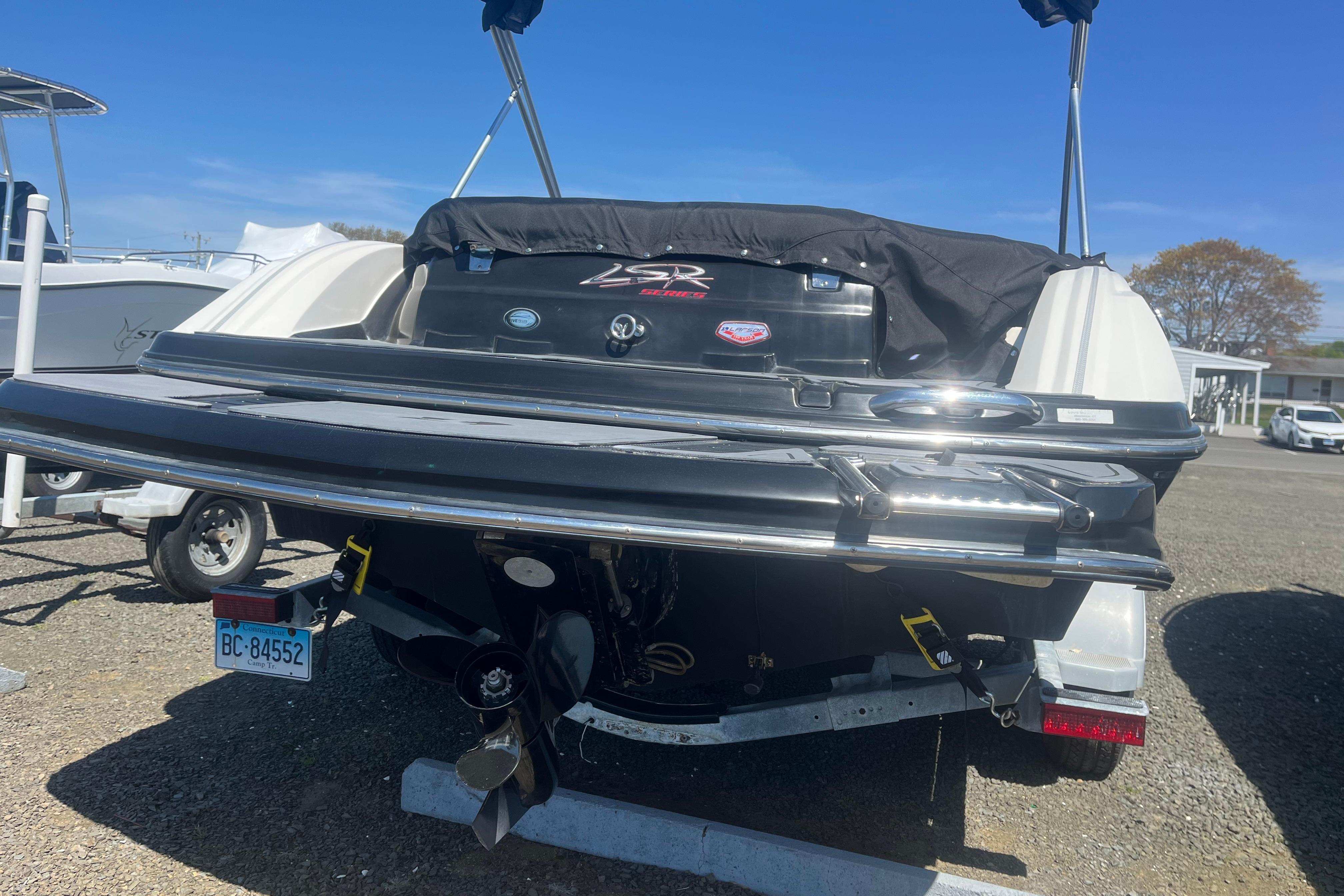 2013 Larson LSR 2300 I/O boat, rear view, parked on a trailer in a sunny outdoor setting.