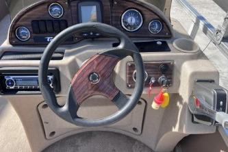 Steering console of a 2012 Avalon Tahoe boat with wood accents and gauges.