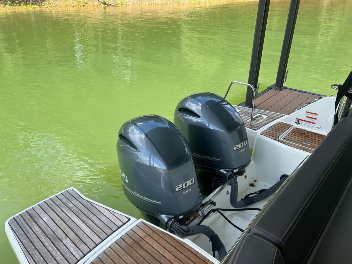 Two outboard engines on a boat in green water.