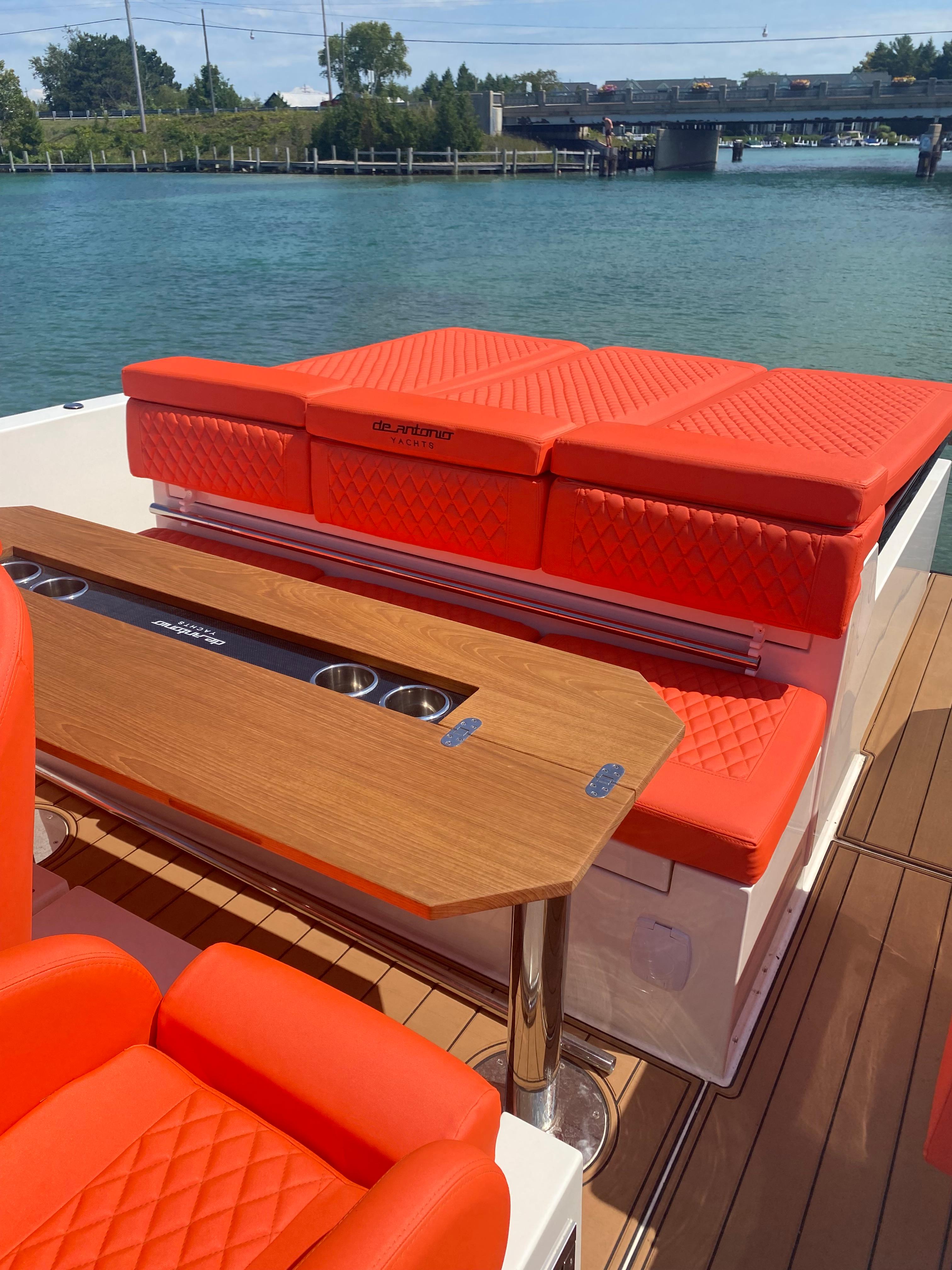 2020 De Antonio Yachts D 28 with red seating and wooden table on deck.