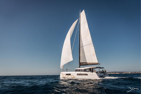 Sailing catamaran Nautitech 44 Open 2025 gliding on open sea under clear blue sky.