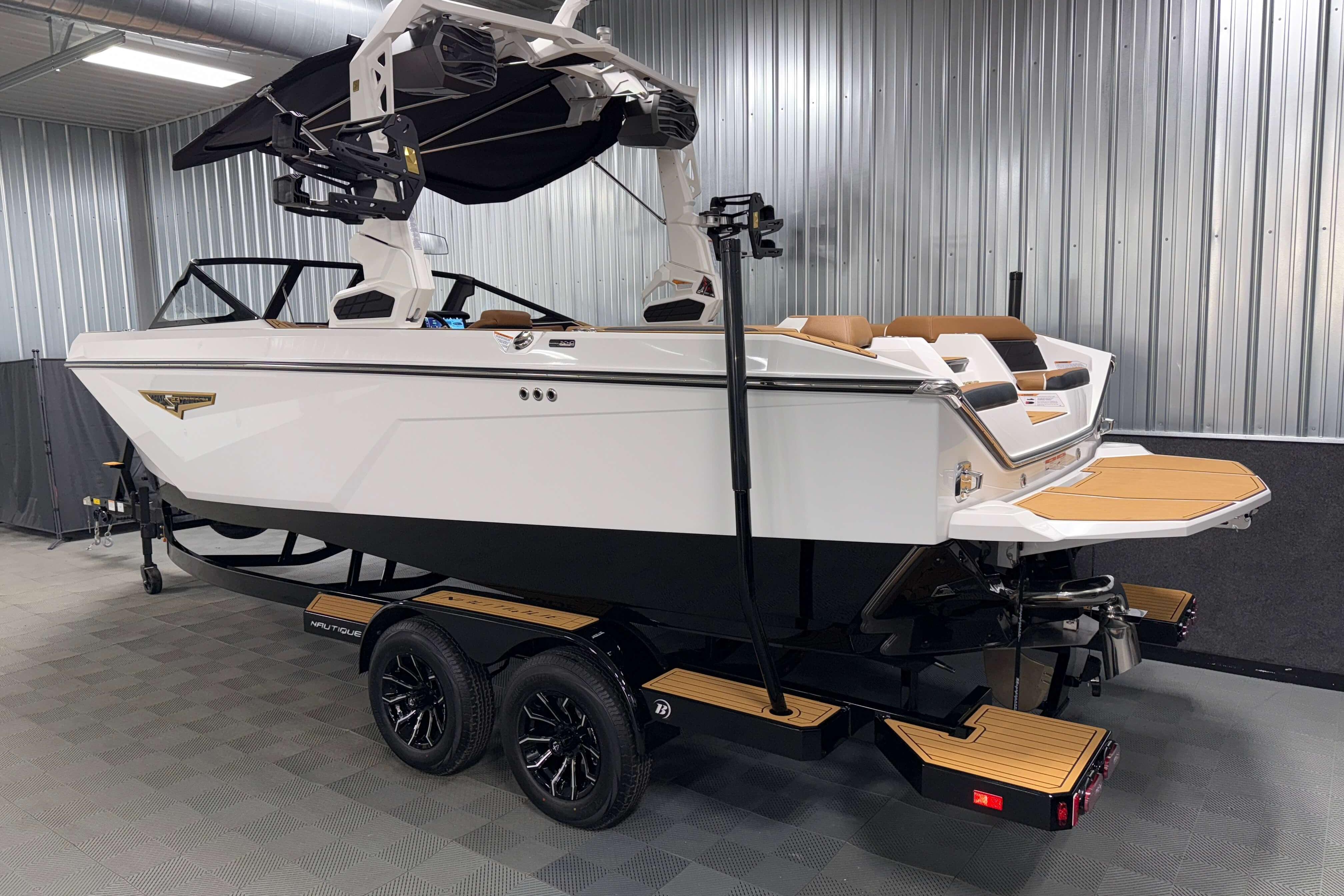 2026 Nautique Super Air Nautique S23 boat in a showroom, side and rear view.