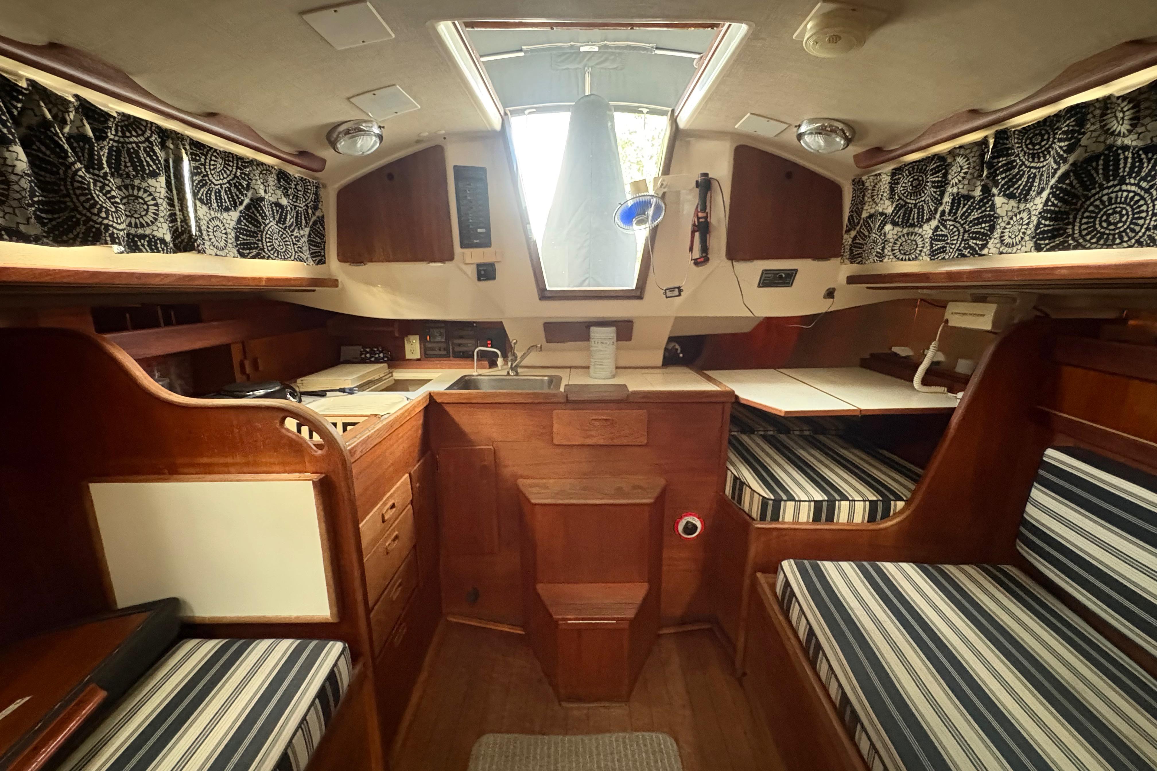 Interior of a 1981 Sabre 31 sailboat with wood finish and striped cushions.
