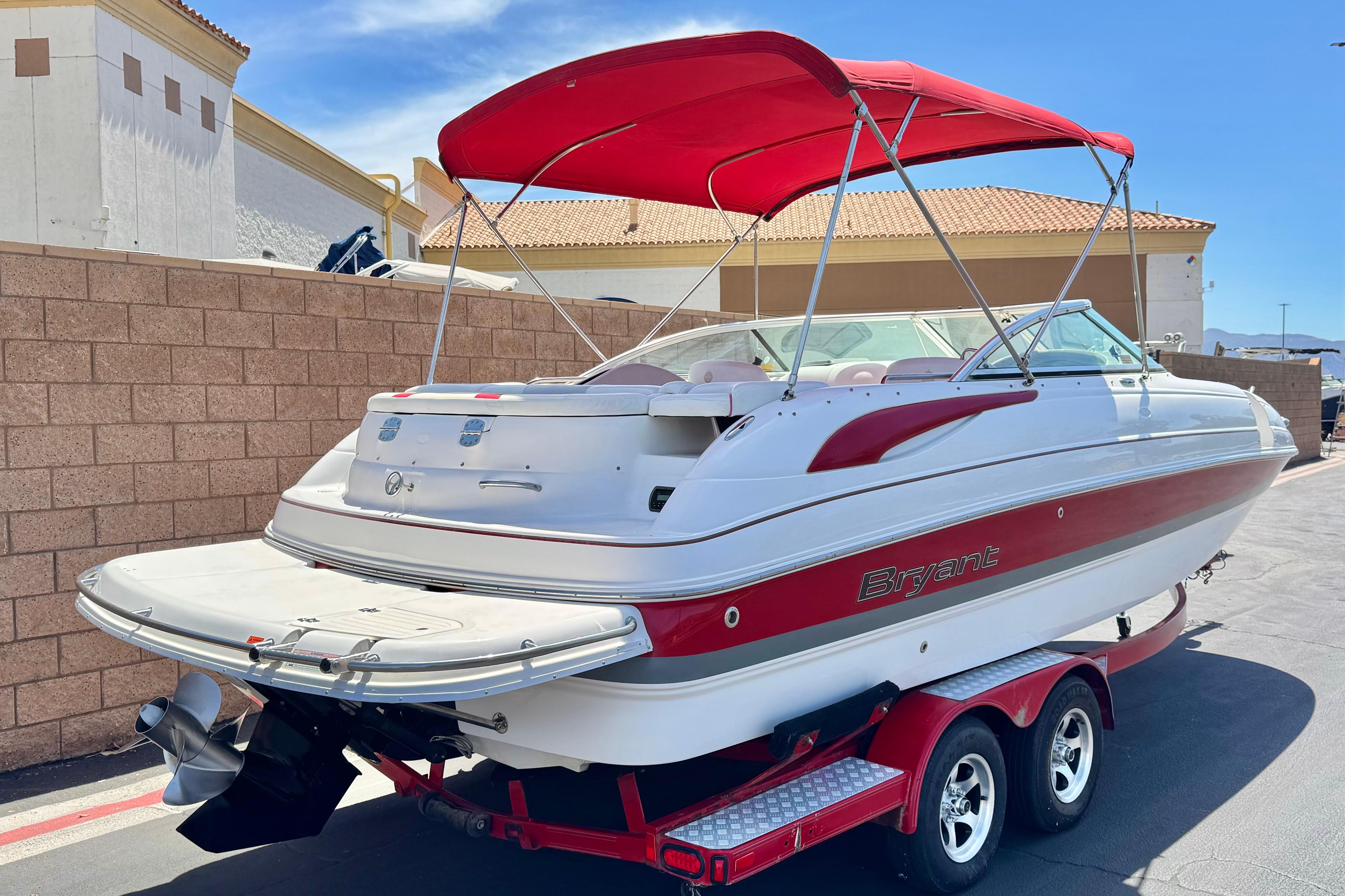 2010 Bryant 255 boat with red canopy on trailer, parked outdoors.