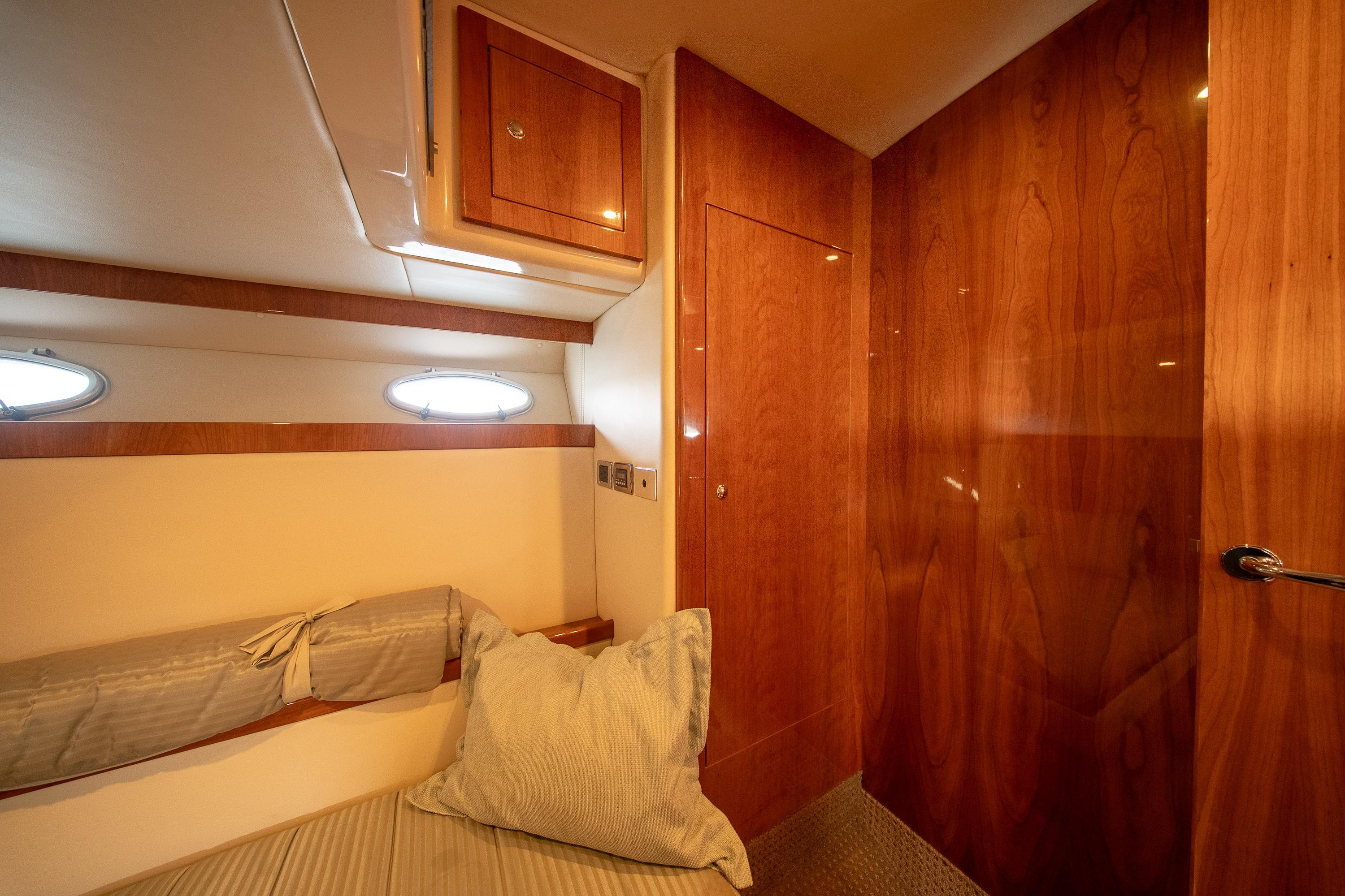 Luxurious cabin interior of 2011 Riviera 5000 Sport Yacht with wood paneling and cozy bedding.