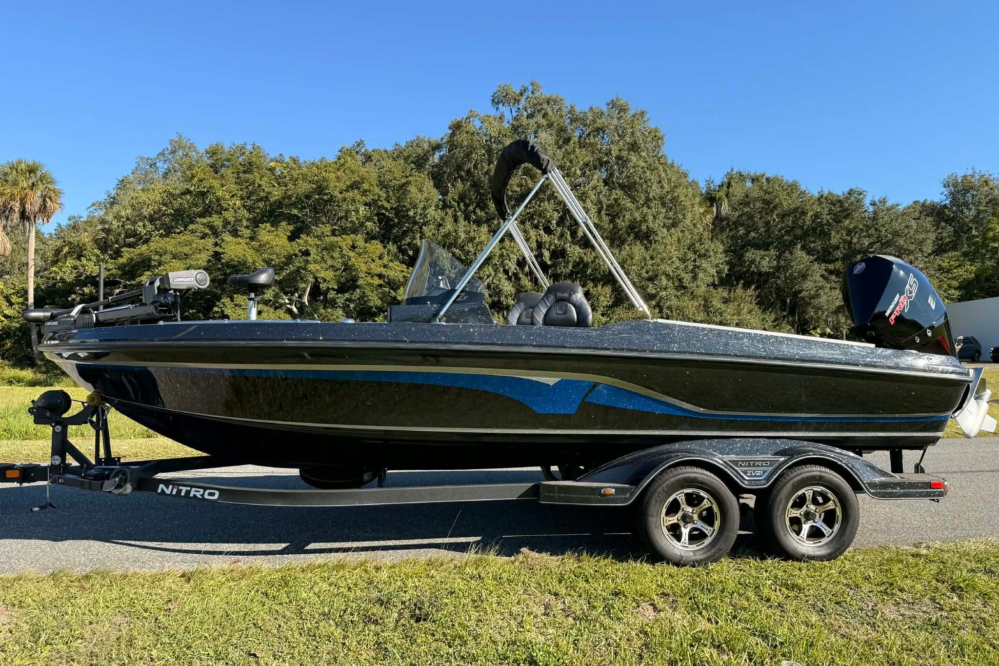 2024 Nitro ZV21 boat on trailer, parked outdoors with trees in background.