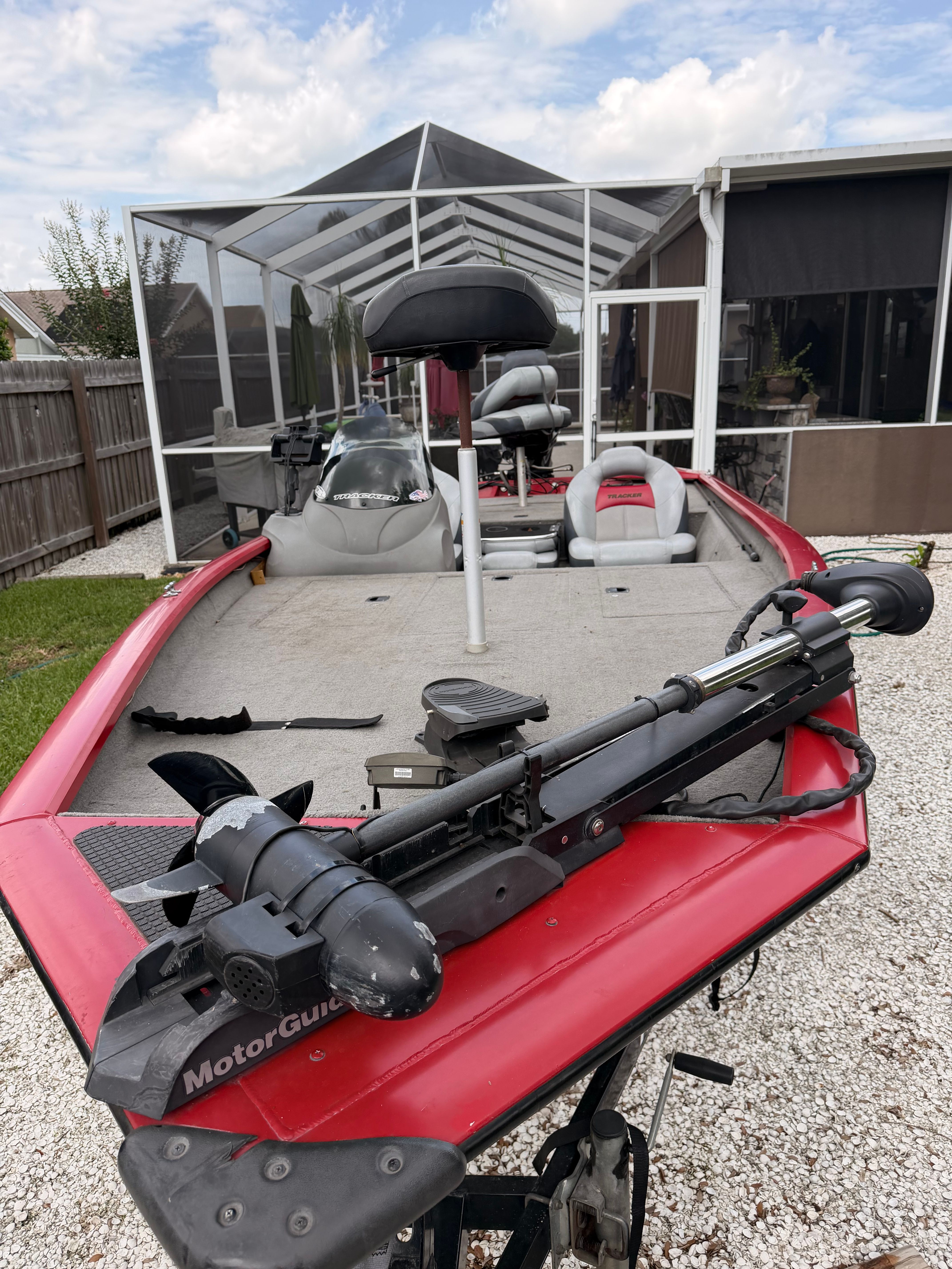 A red 2011 Bass Tracker PRO TEAM 175 TXW boat is parked on a gravel area.