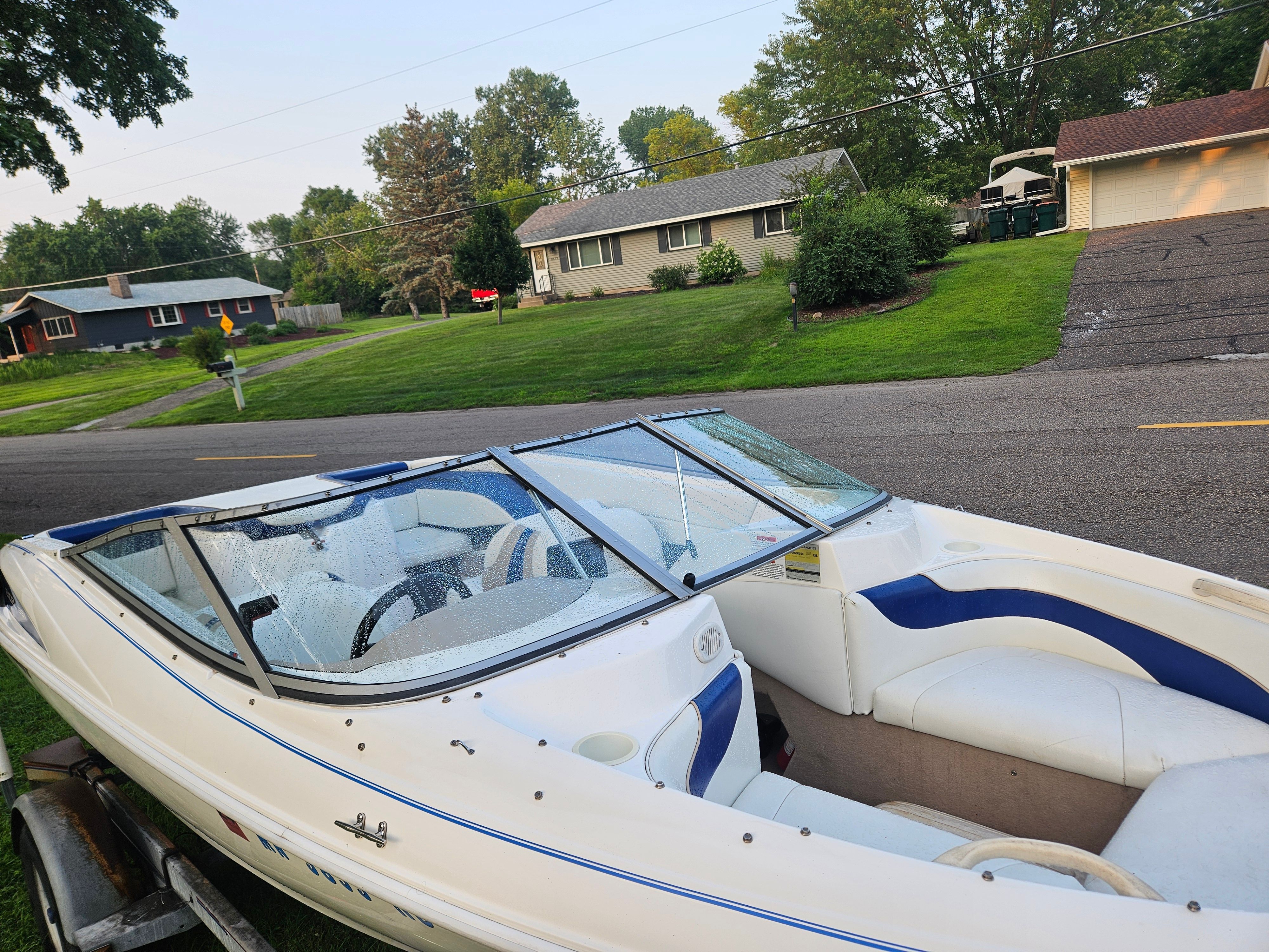 A 1996 Wellcraft Excel boat on a trailer in a residential area.
