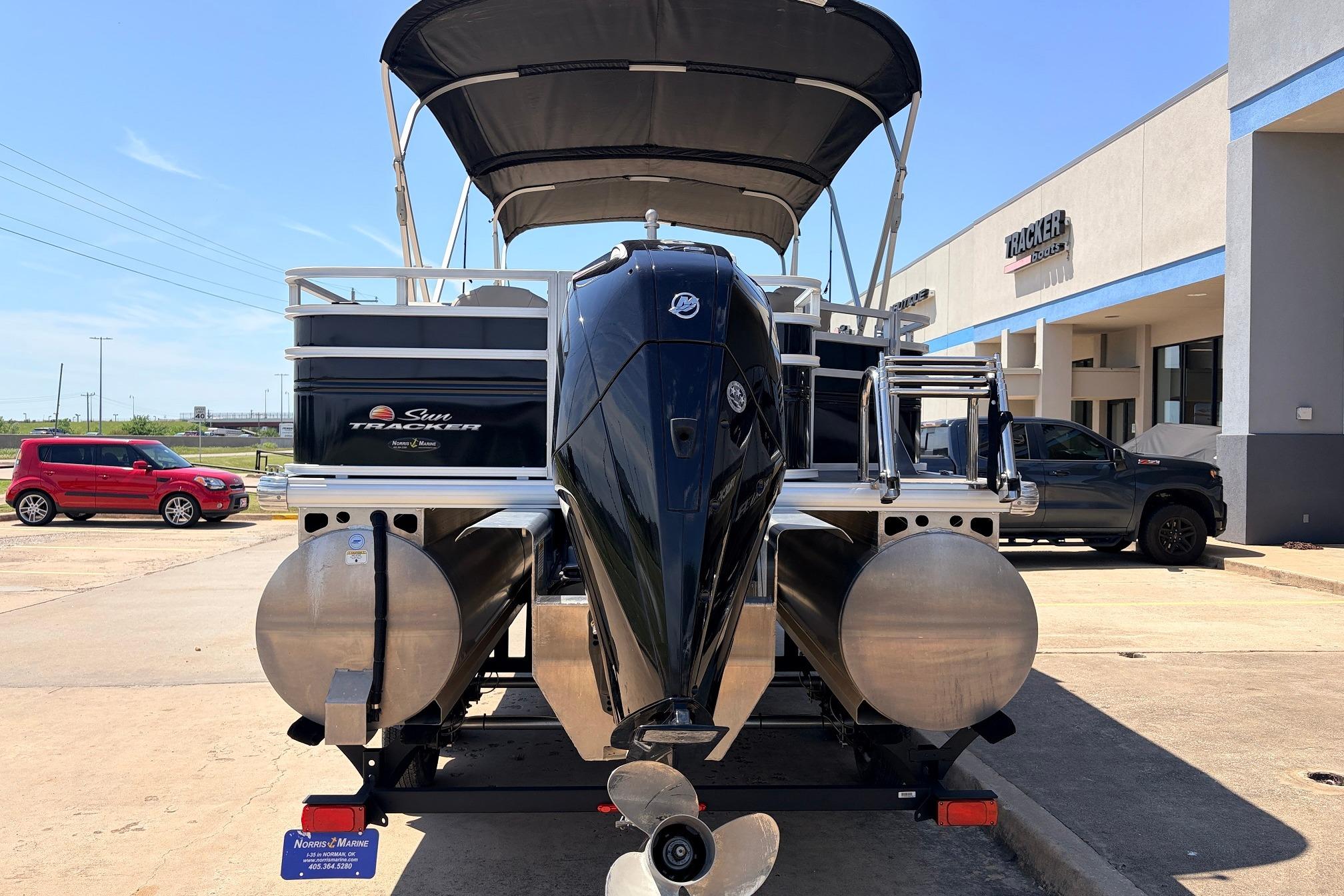 2024 Sun Tracker SportFish 22 XP3 pontoon boat with outboard motor, parked outside dealership.