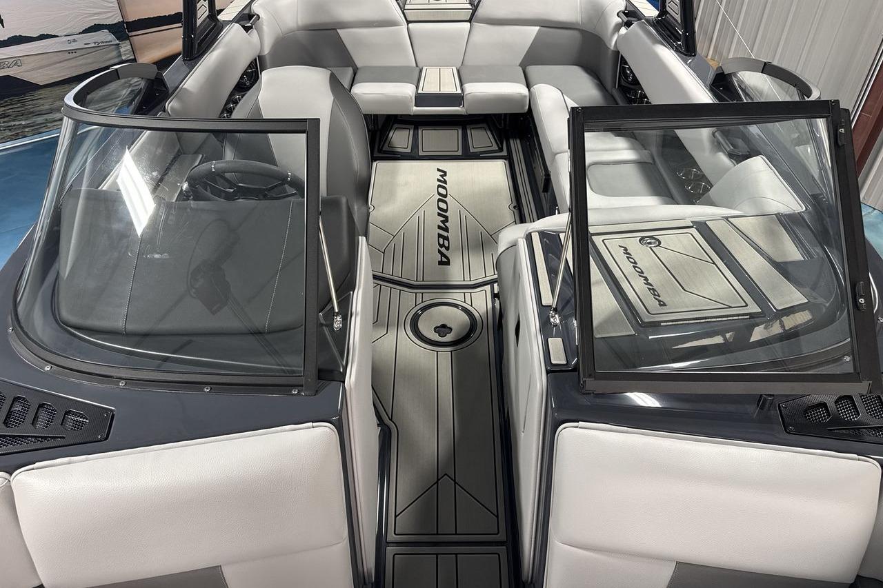 Interior view of a modern Moomba Craz boat with gray seating and glass windows.