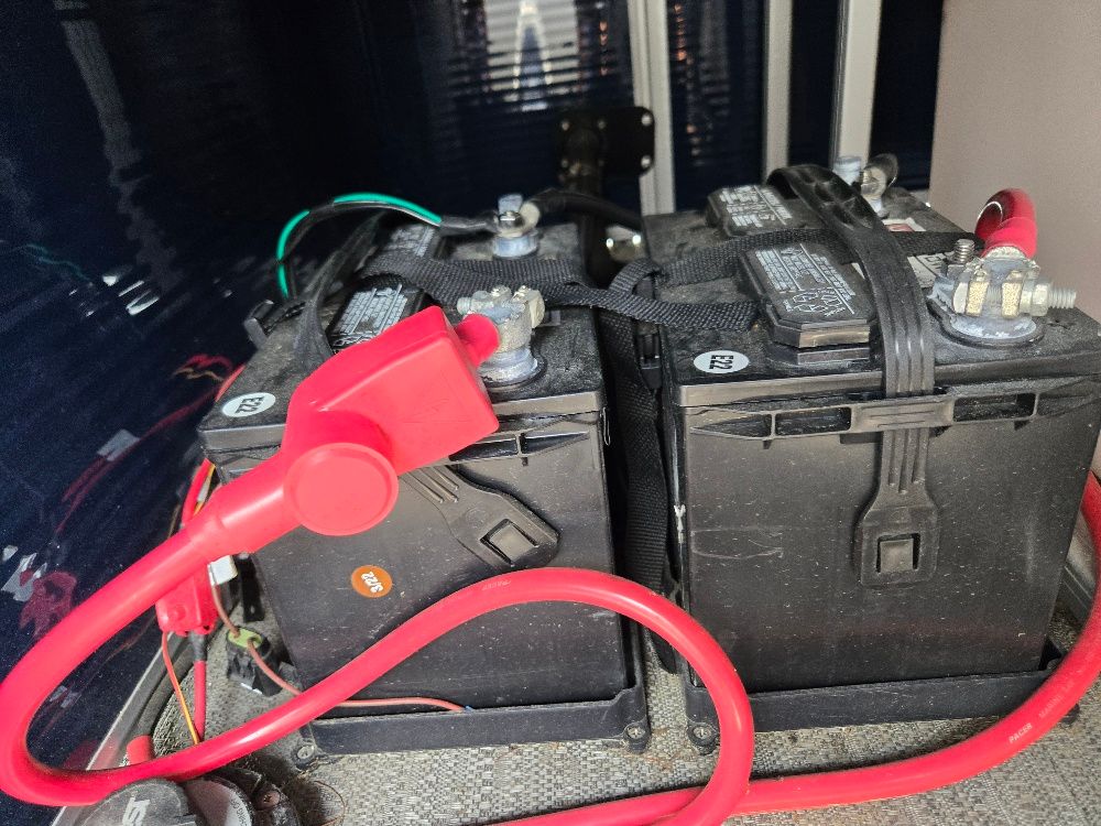 Two black batteries with red cables are installed in a boat.