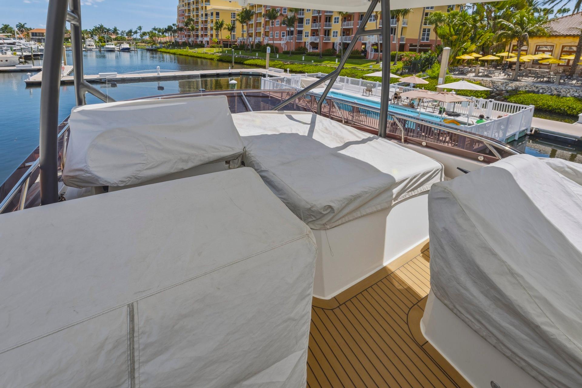 Luxury 2022 Prestige 520 yacht deck with covered seating, docked in a scenic marina.