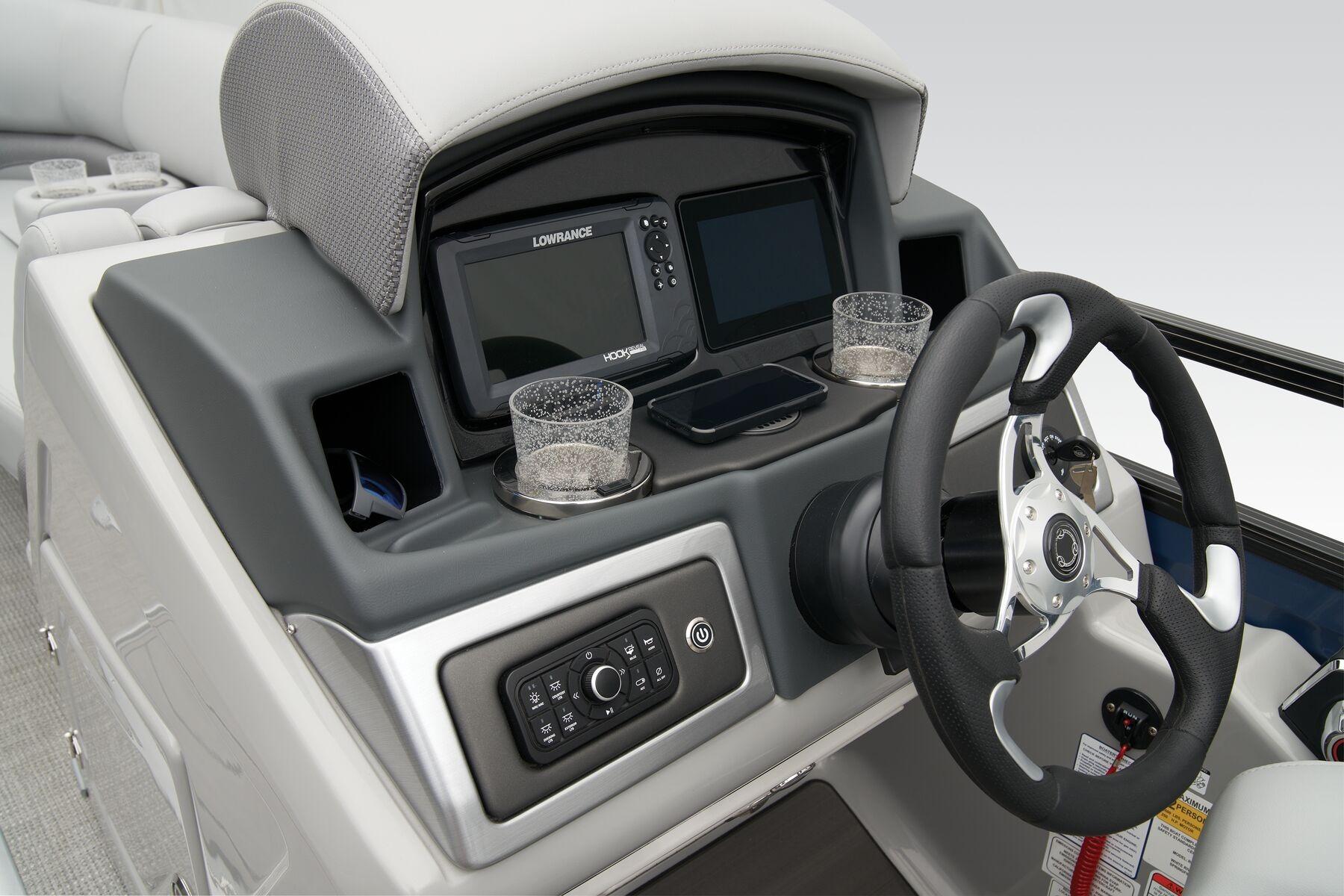 2026 Regency 230 DL boat dashboard with steering wheel, navigation system, and cup holders.