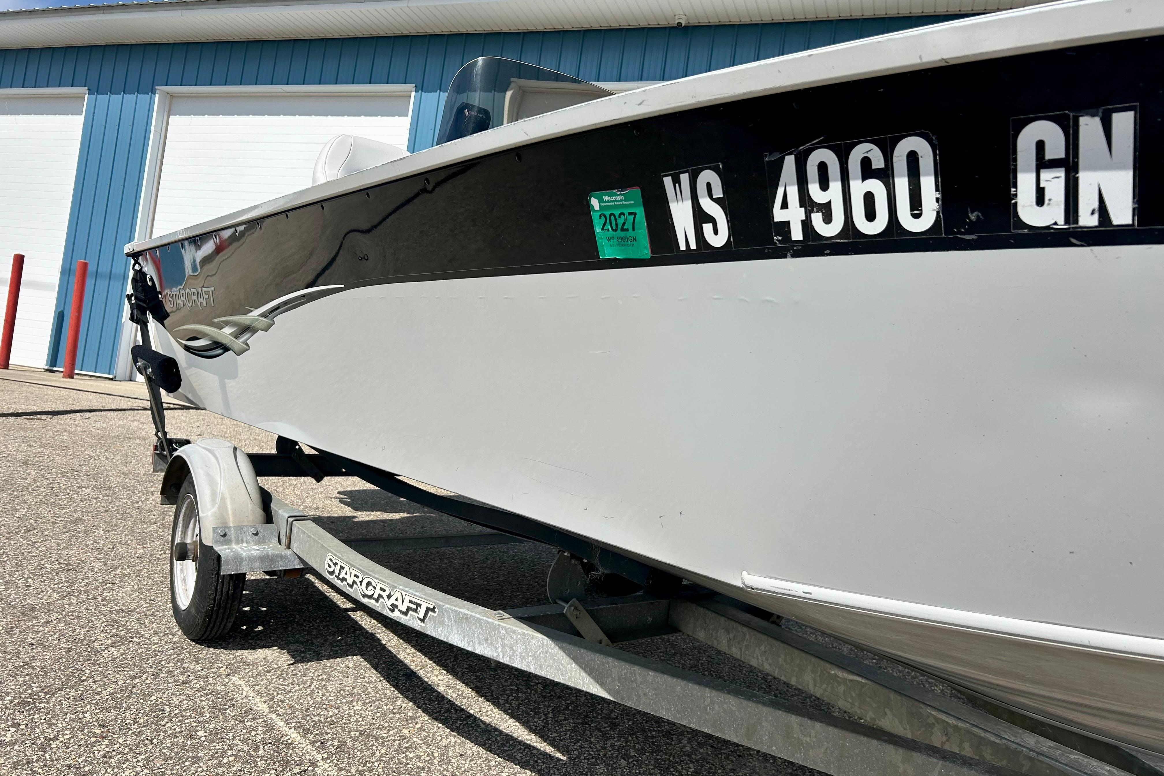 2004 Starcraft D-Star 160 DLX SC boat on trailer, parked near blue building.