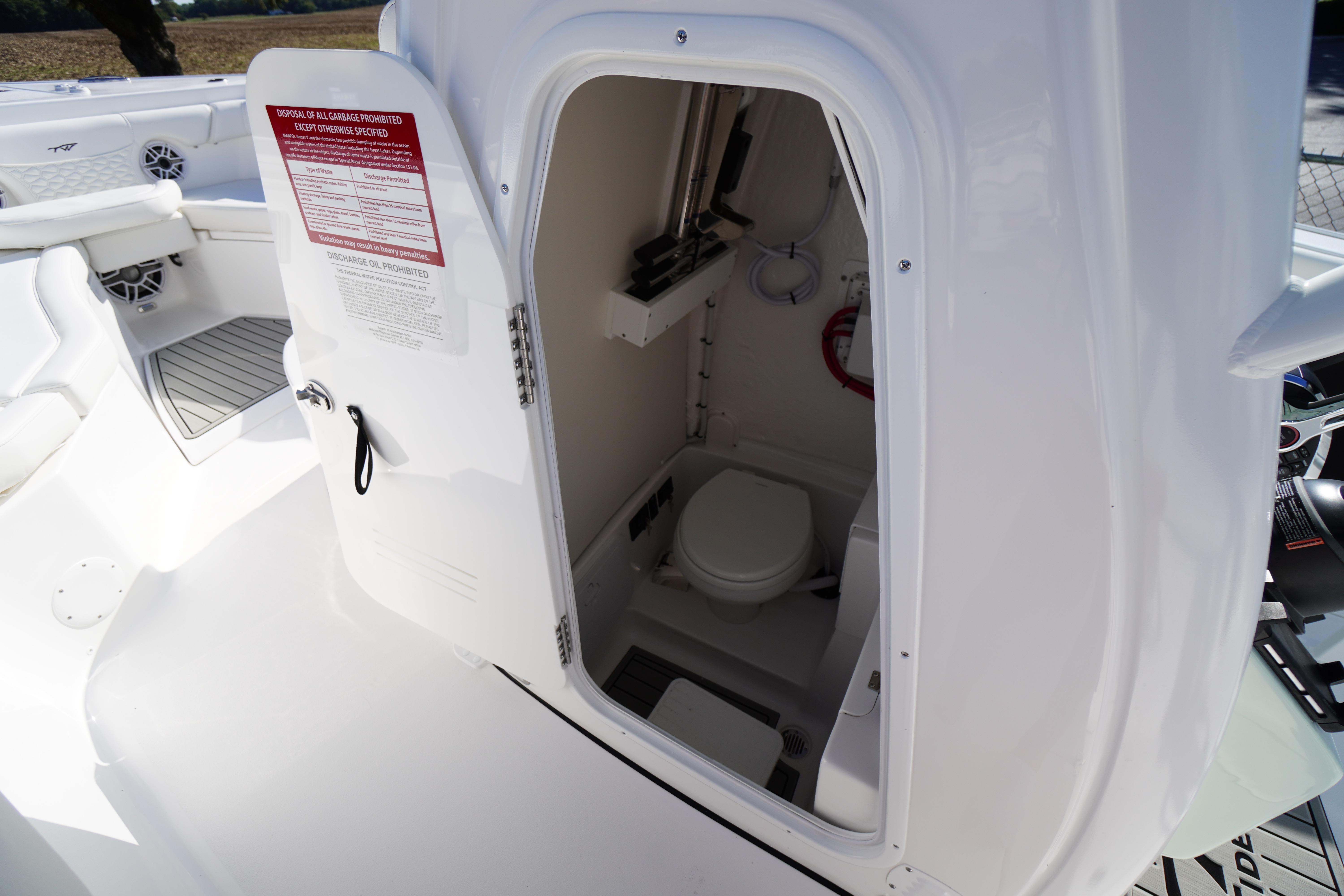 2026 Tidewater 272 LXF boat interior with open door revealing compact marine toilet.