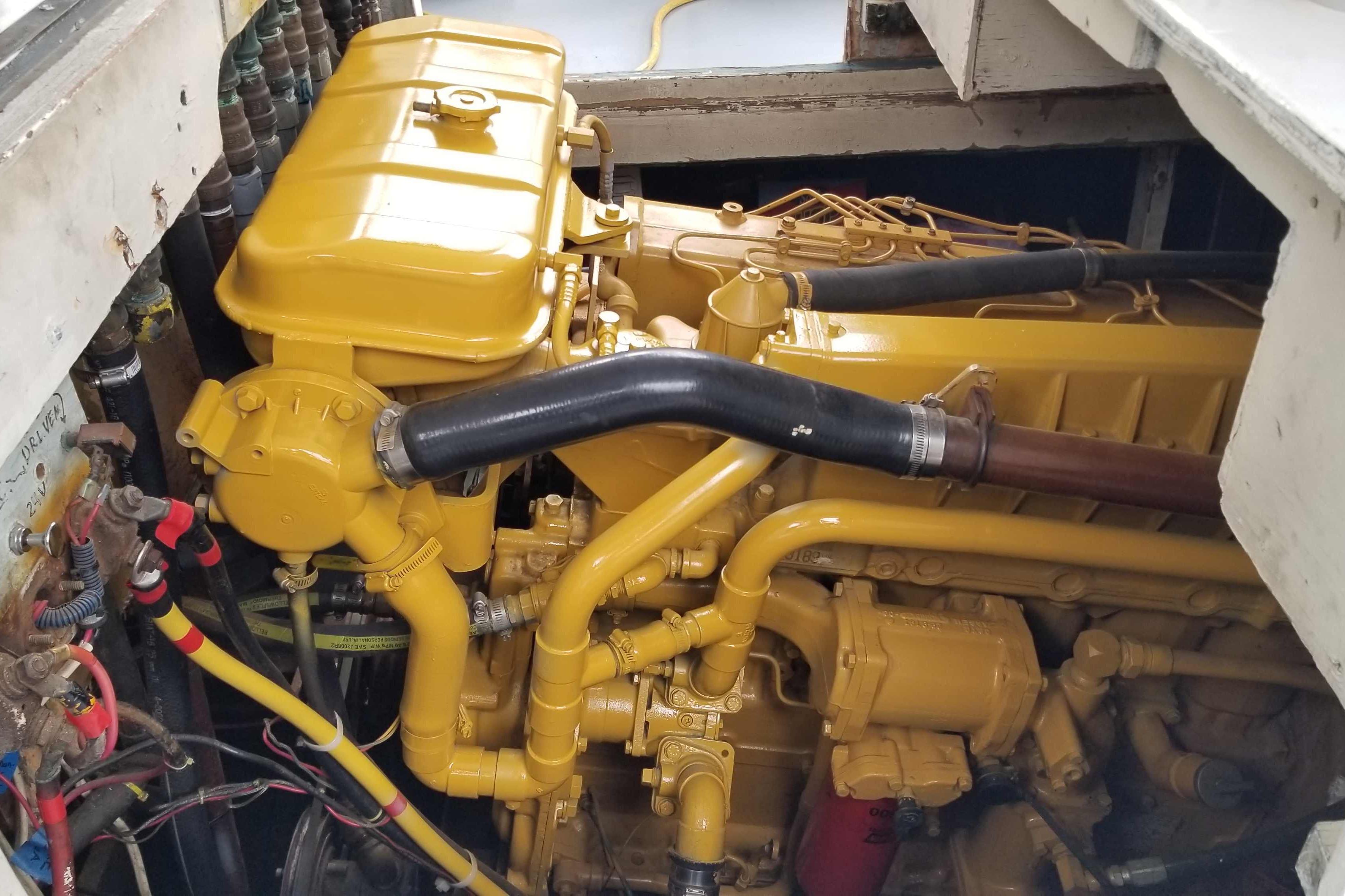 Yellow engine inside a 1964 Grandy Tour Boat, showcasing detailed mechanical components.