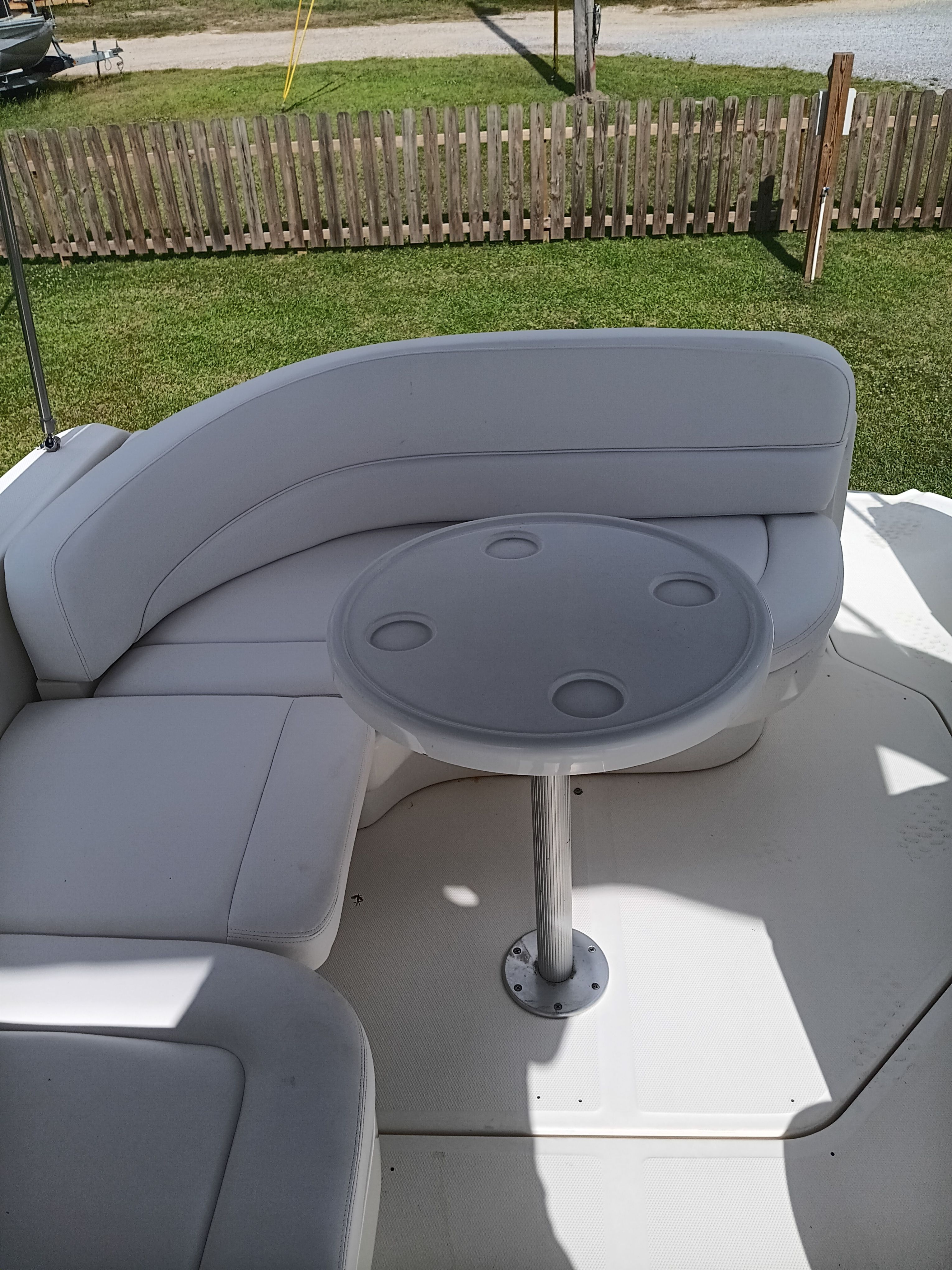 The image shows a white seating area with a round table on a boat.
