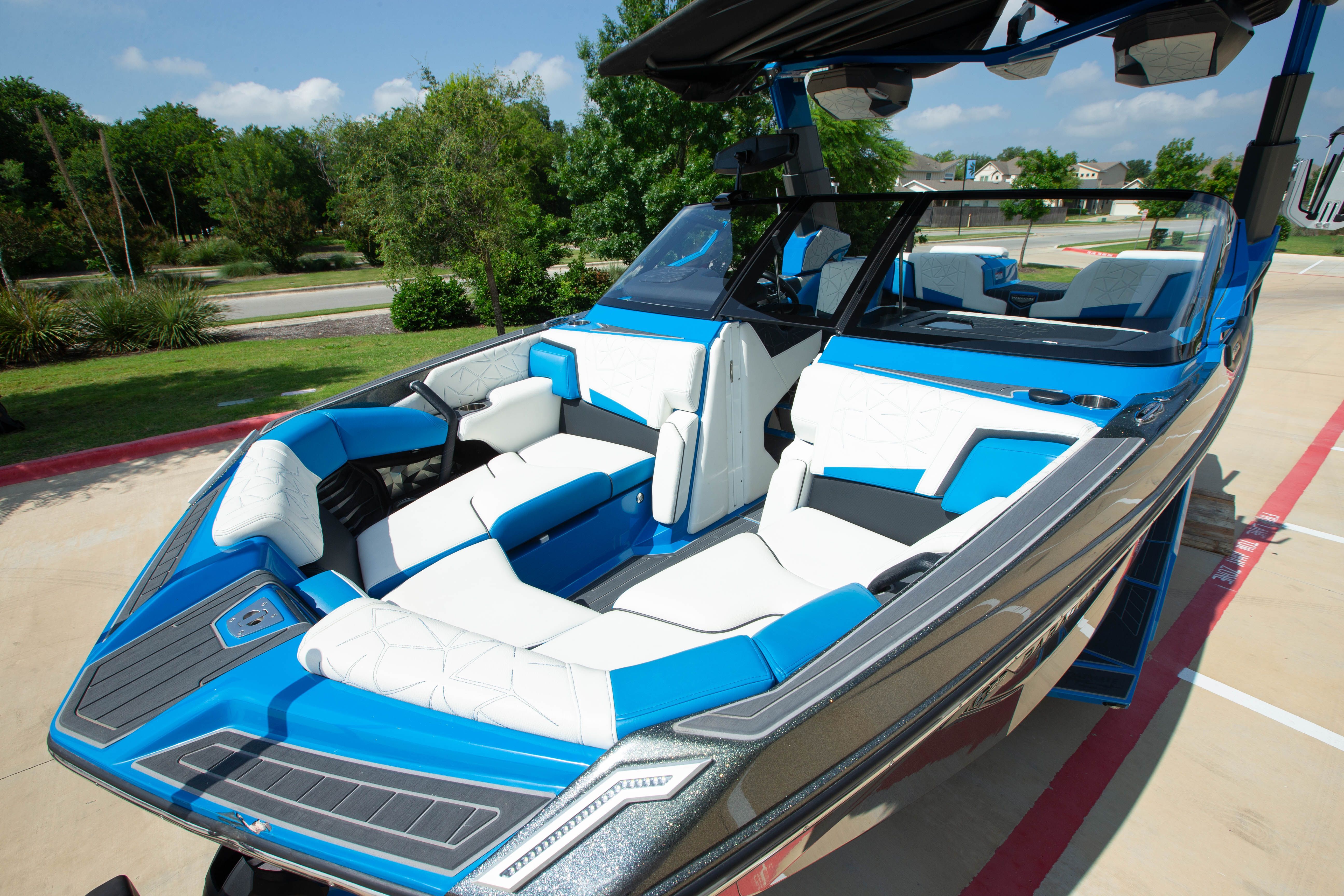 A luxurious boat with blue and white seating, parked on a concrete lot.