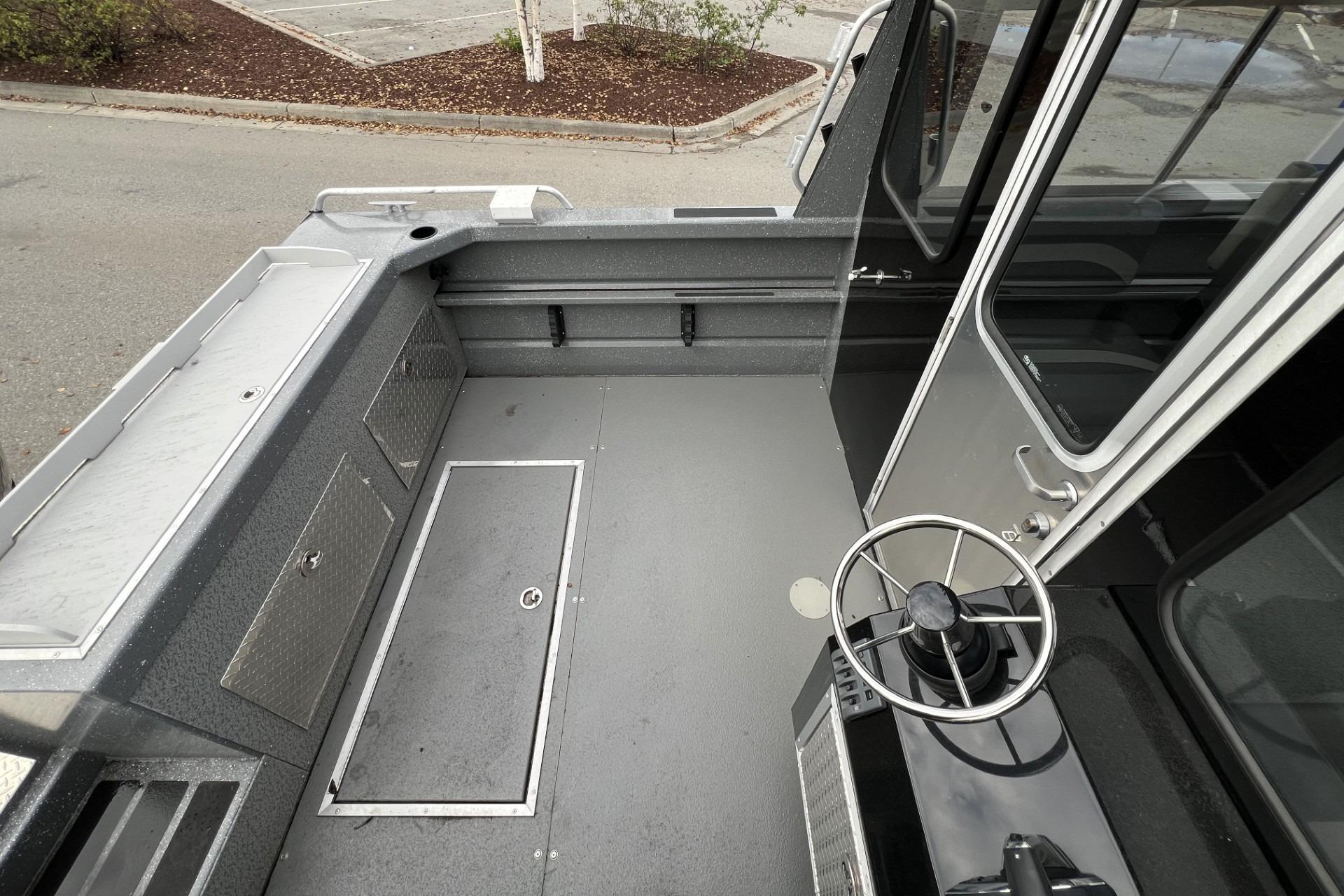 2024 Spartan 220 Maximus boat interior with steering wheel and storage compartments.