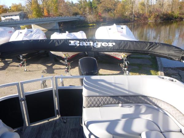 2024 Ranger Reata 223C pontoon boat with covered motor, docked near a serene lake.